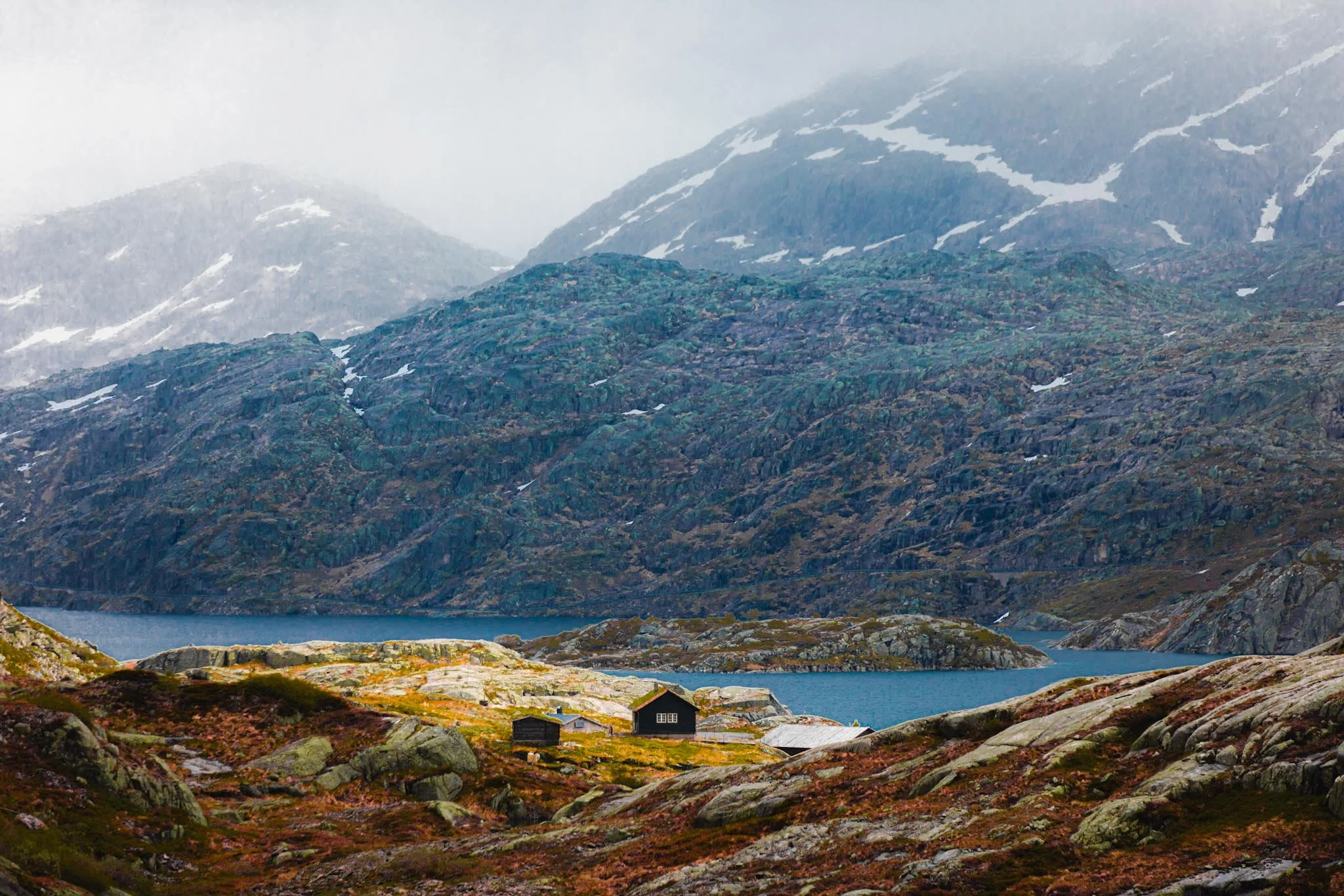 Small cabin in a Norwegian mountain valley with light hitting only part of the landscape