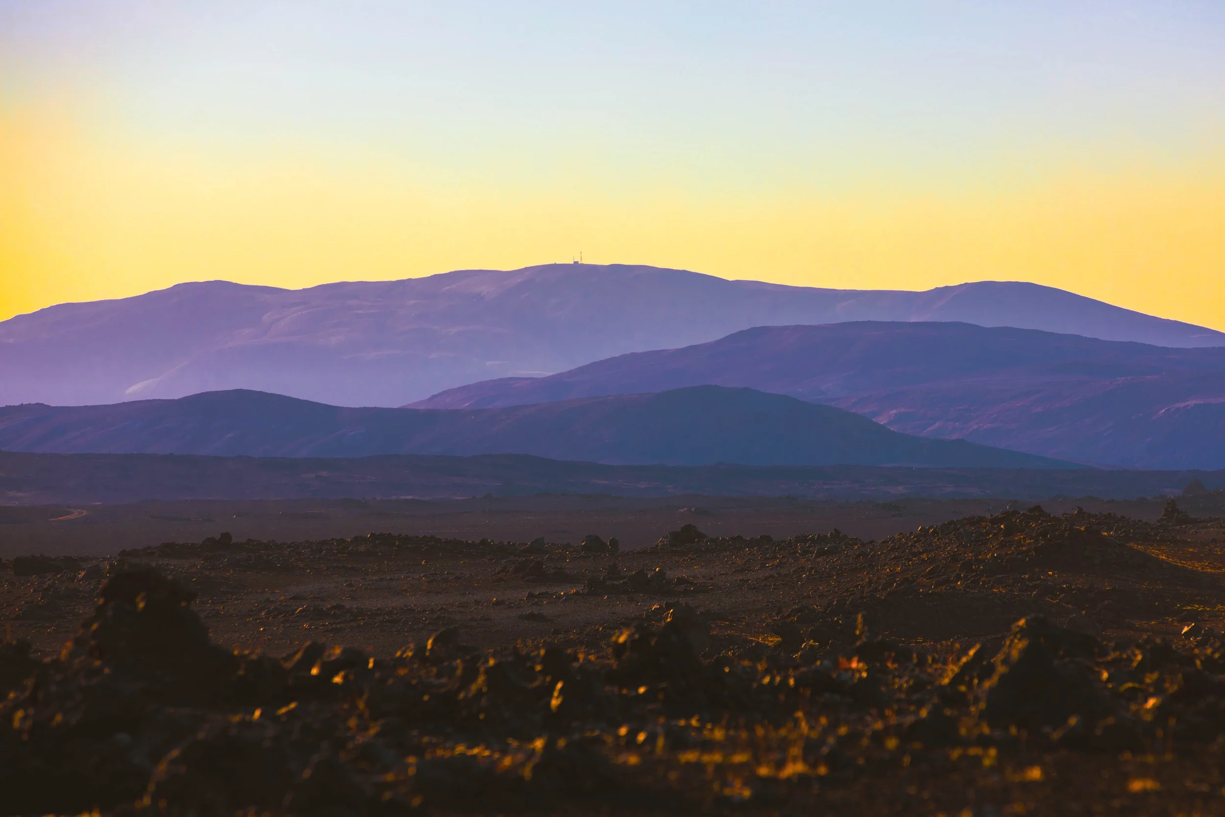 Layered mountain landscape in Iceland with warm sunset sky and cool blue tones in the distant hills