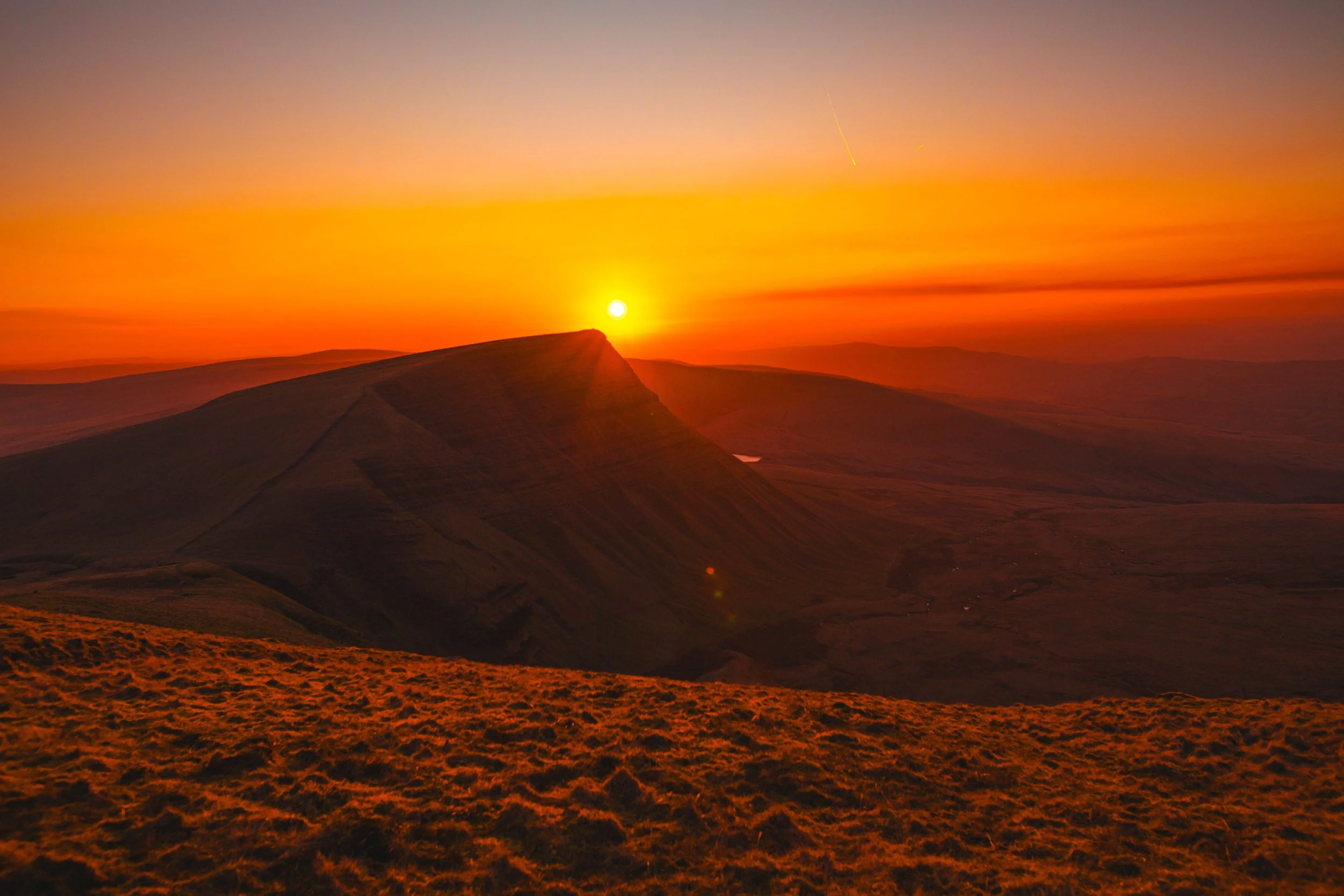 Warm sunset light over Pen y Fan ridge in the Brecon Beacons creating strong orange tones across the landscape
