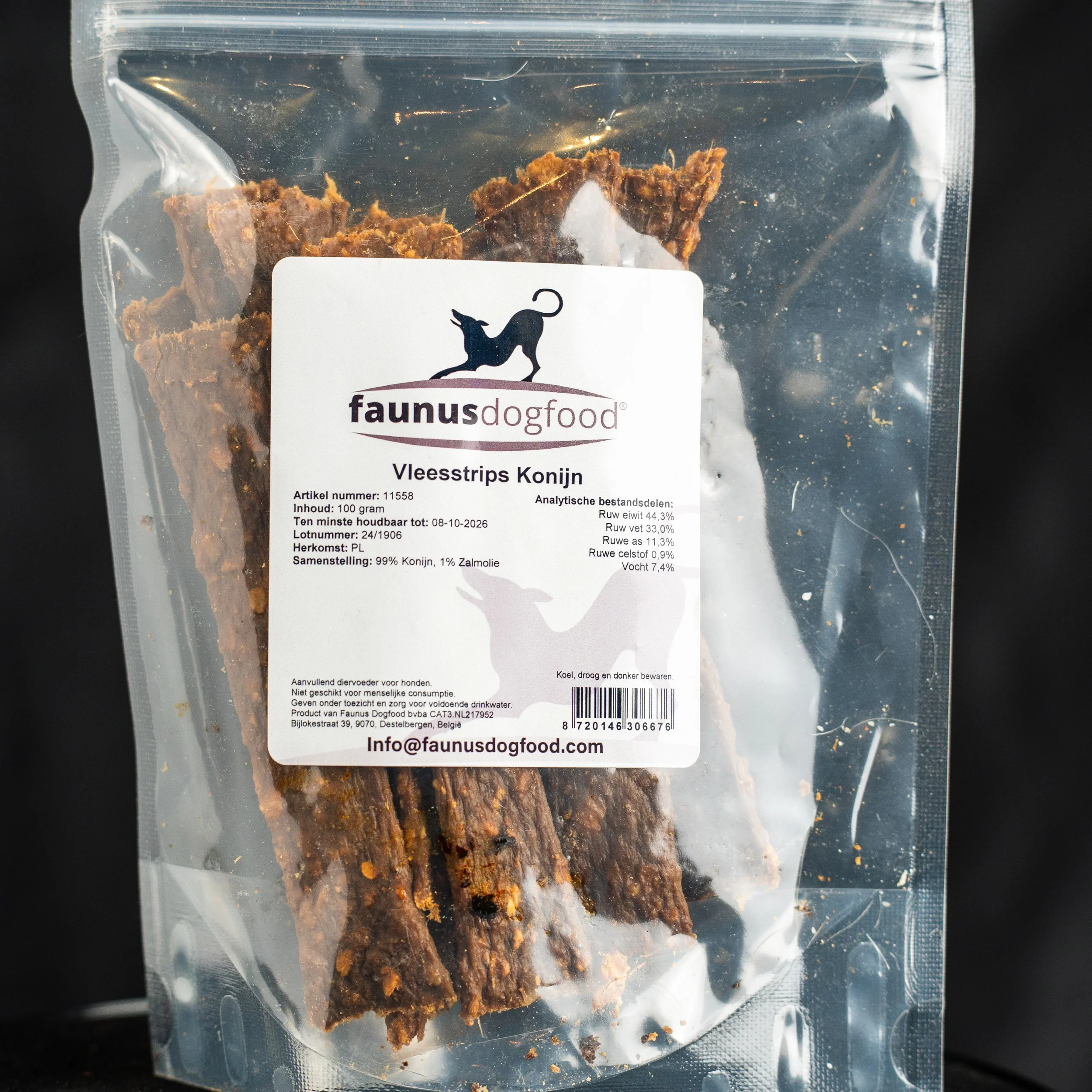 Dog treats in a clear plastic bag with a white label from Faunus dog food, featuring a black dog silhouette and nutritional information, on a black background.