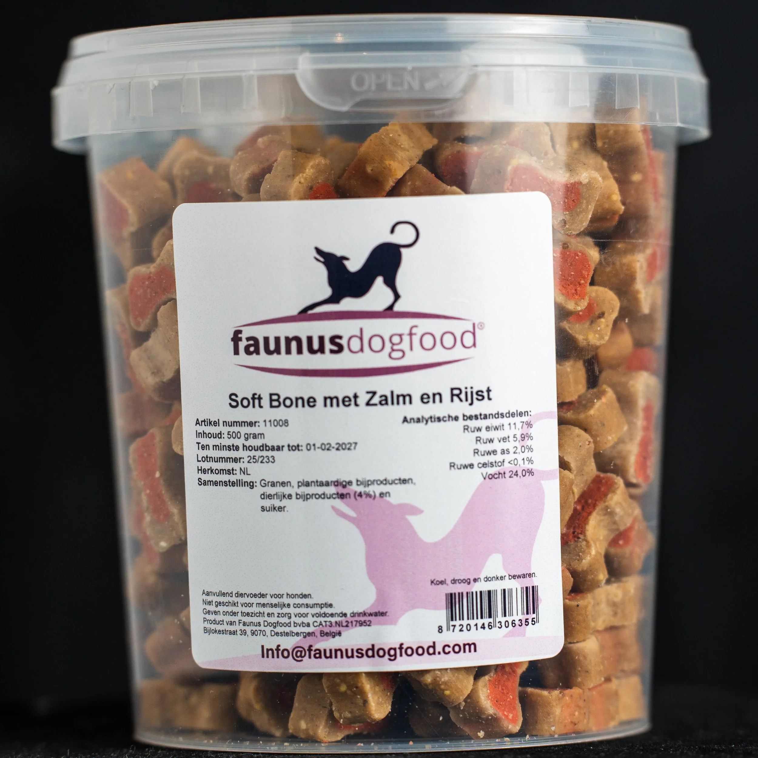 Clear plastic container filled with dog treats shaped like small bones, labeled 'faunus dogfood' with details in Dutch. The label features a silhouette of a dog and a cat, and states the treats are made of bones with salmon and rice.