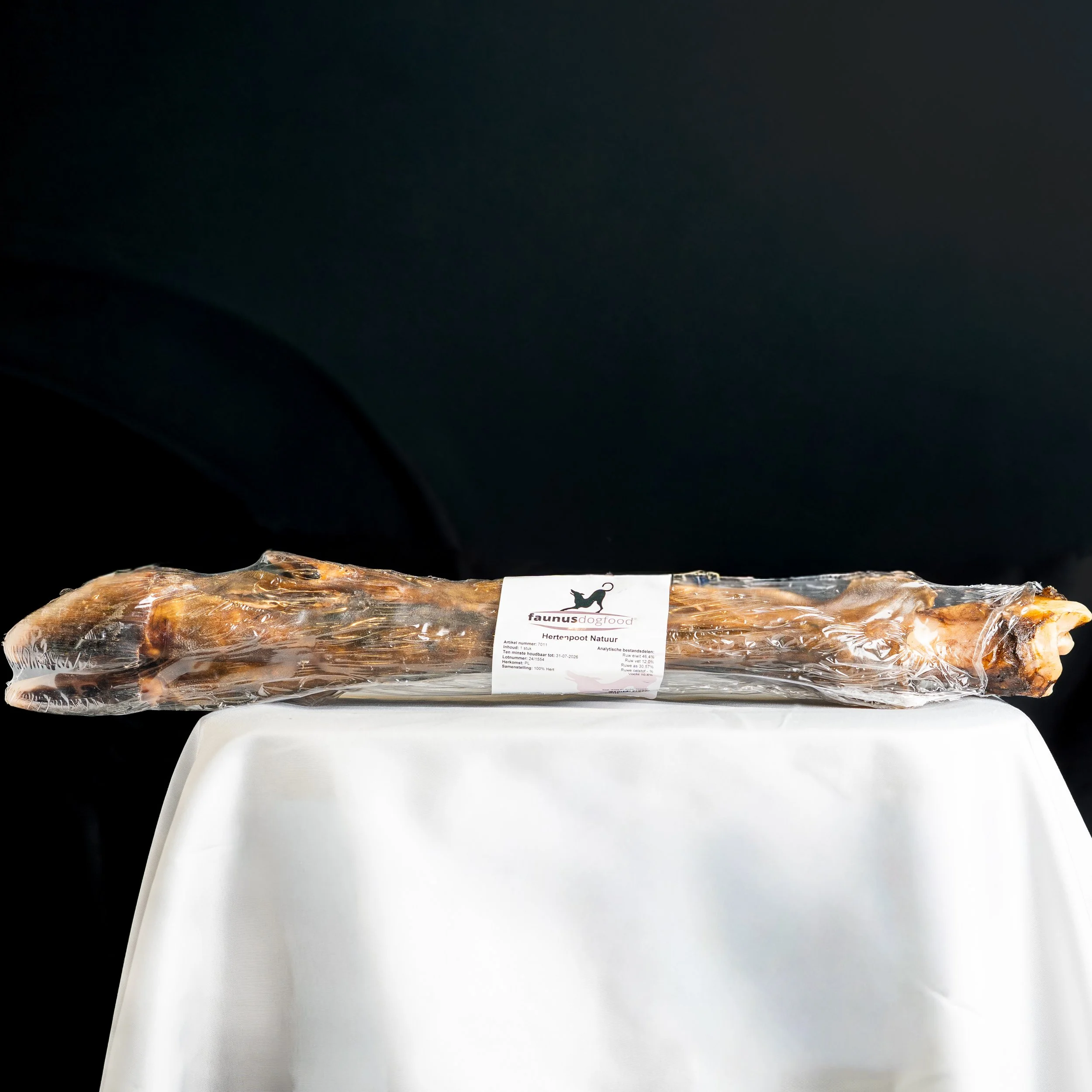 Wrapped dog treat placed on white surface against black background.