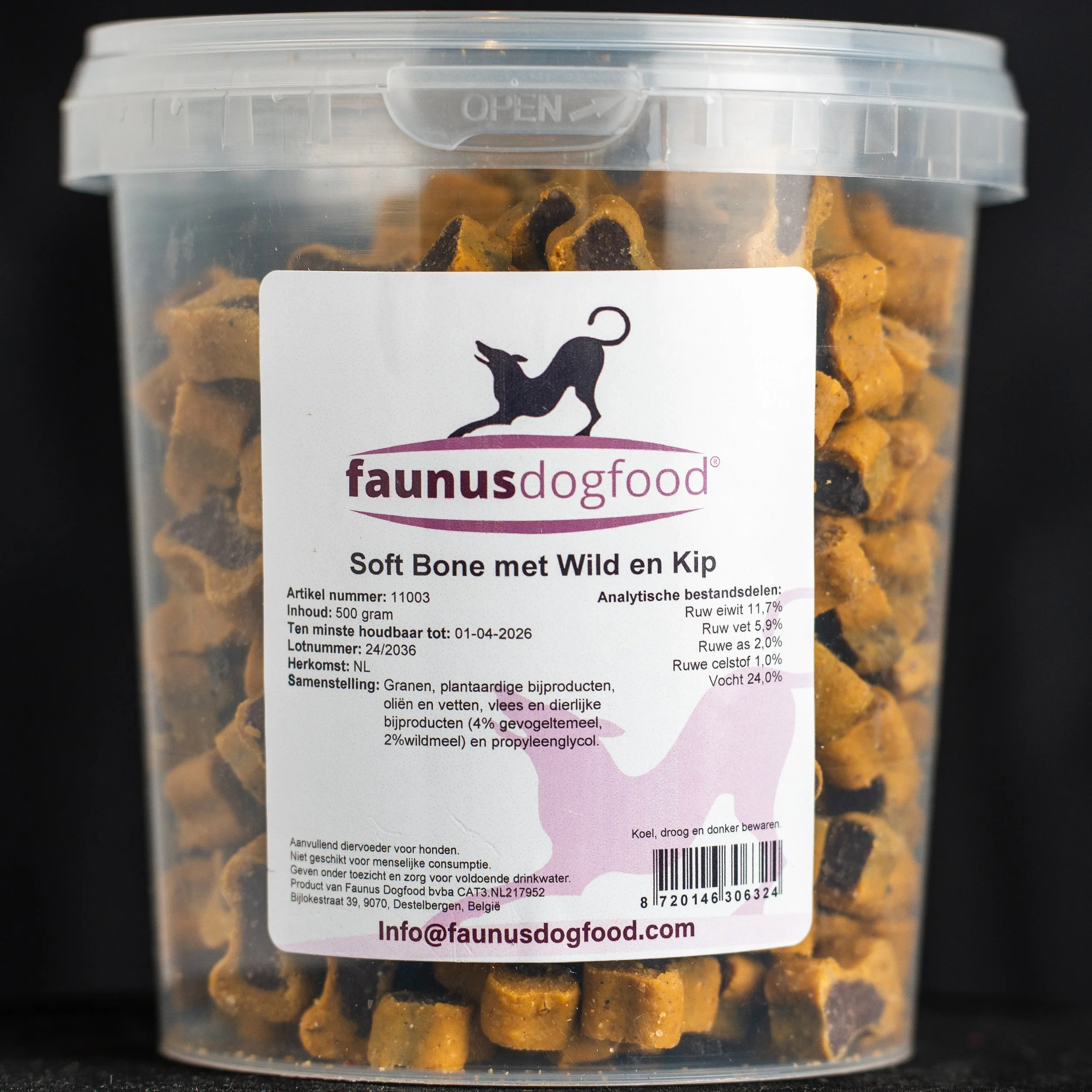 A clear plastic container with a white label containing dog food called 'Soft Bone met Wild en Kip', with kibble pieces inside.