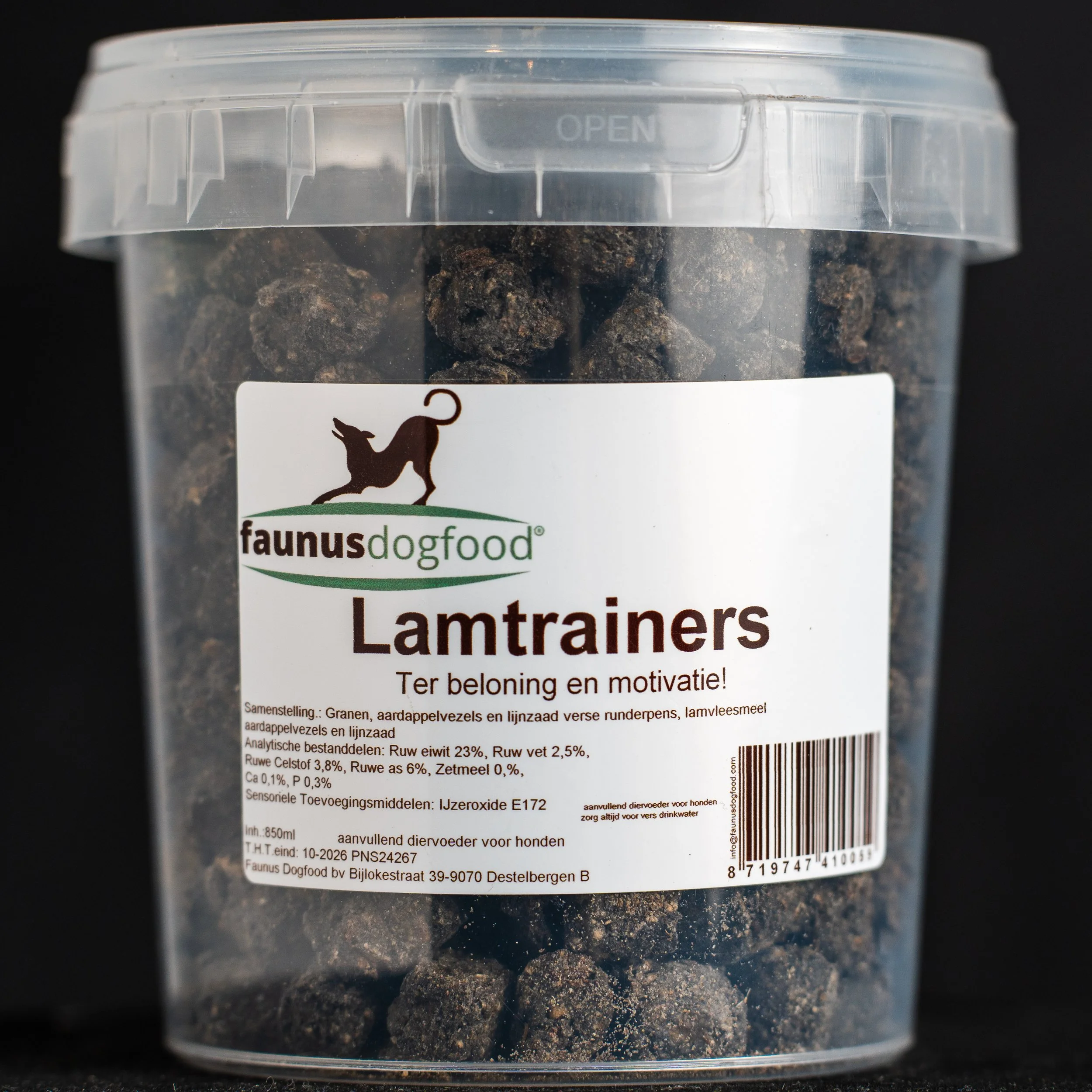 A transparent plastic container with a clear lid labeled 'Lamtrainers' from faunus dog food, containing black dog treats shaped like small balls.