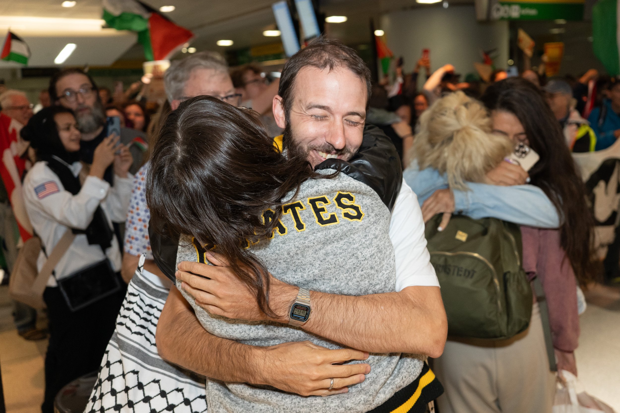 People at an airport or station embracing and greeting each other, indicating a joyful reunion.