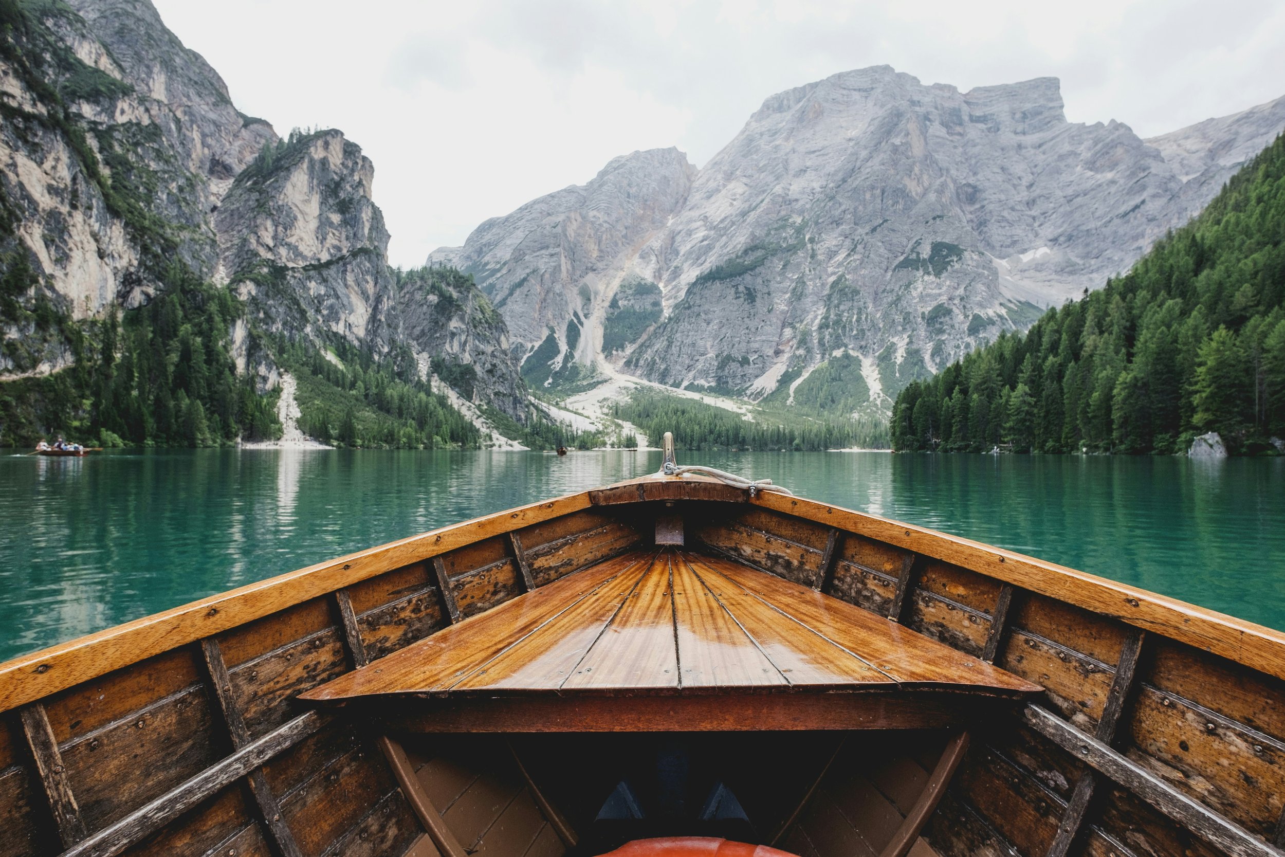 View from a boat on a lake surrounded by mountains and forests.