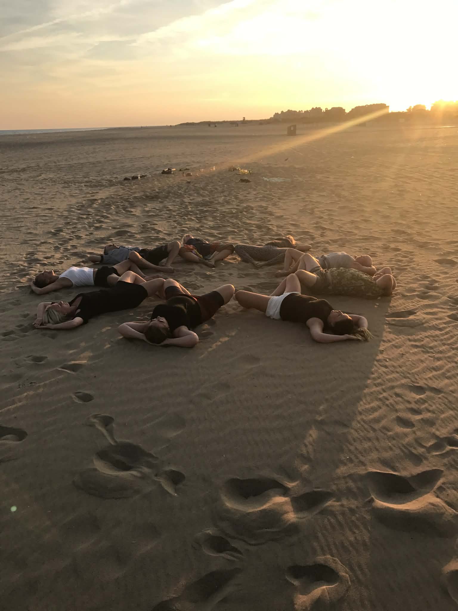 Group of people lying on the sandy beach at sunset.