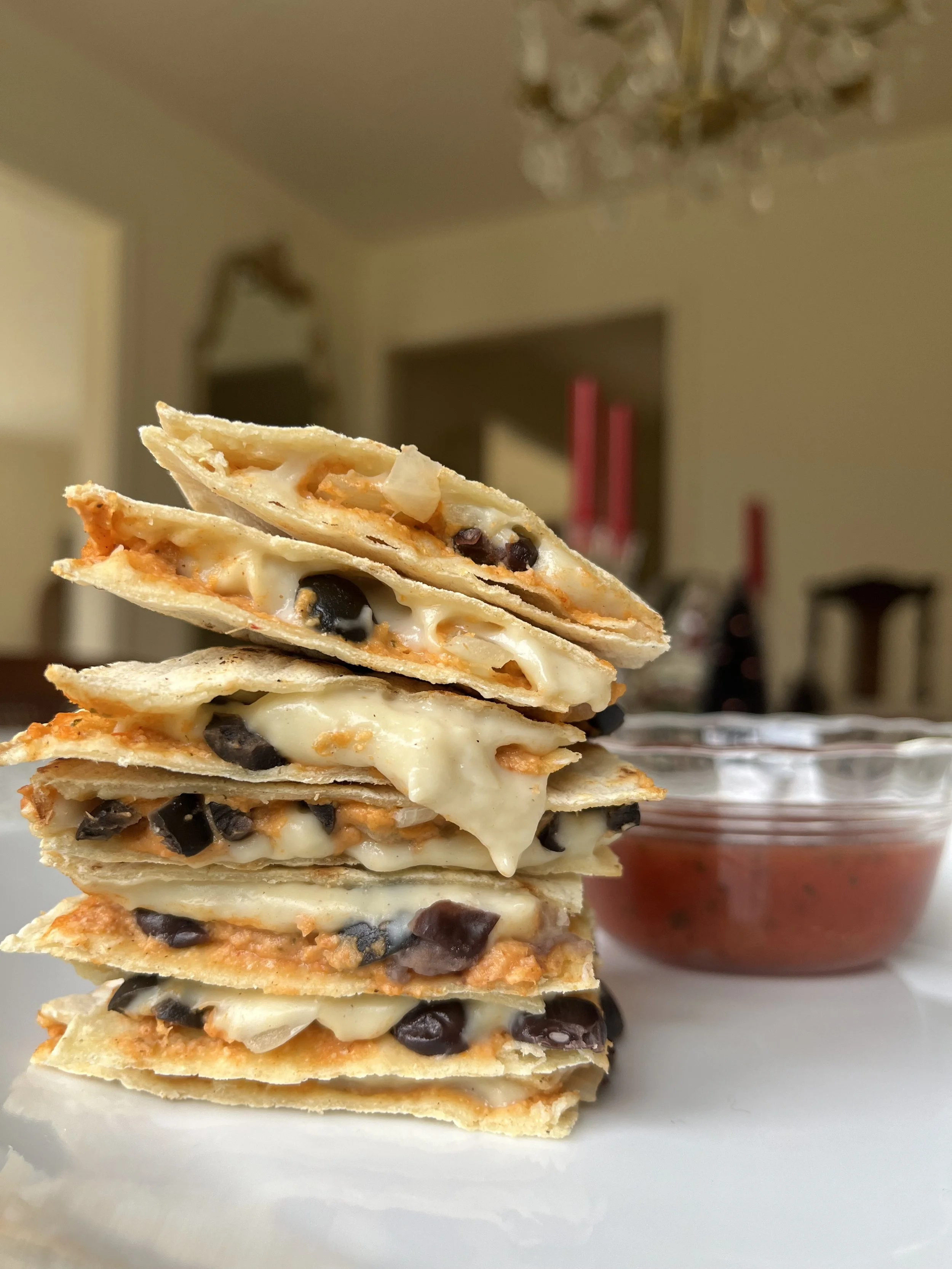Stack of five cheese and black bean quesadilla slices with a side of salsa