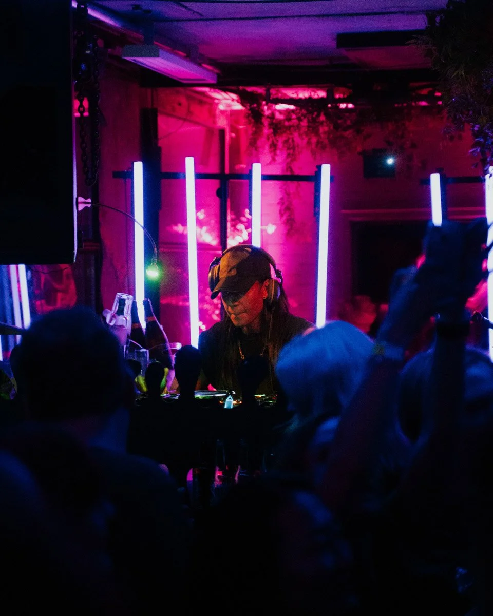 En DJ som spiller musikk på en nattklubb med farget lys.