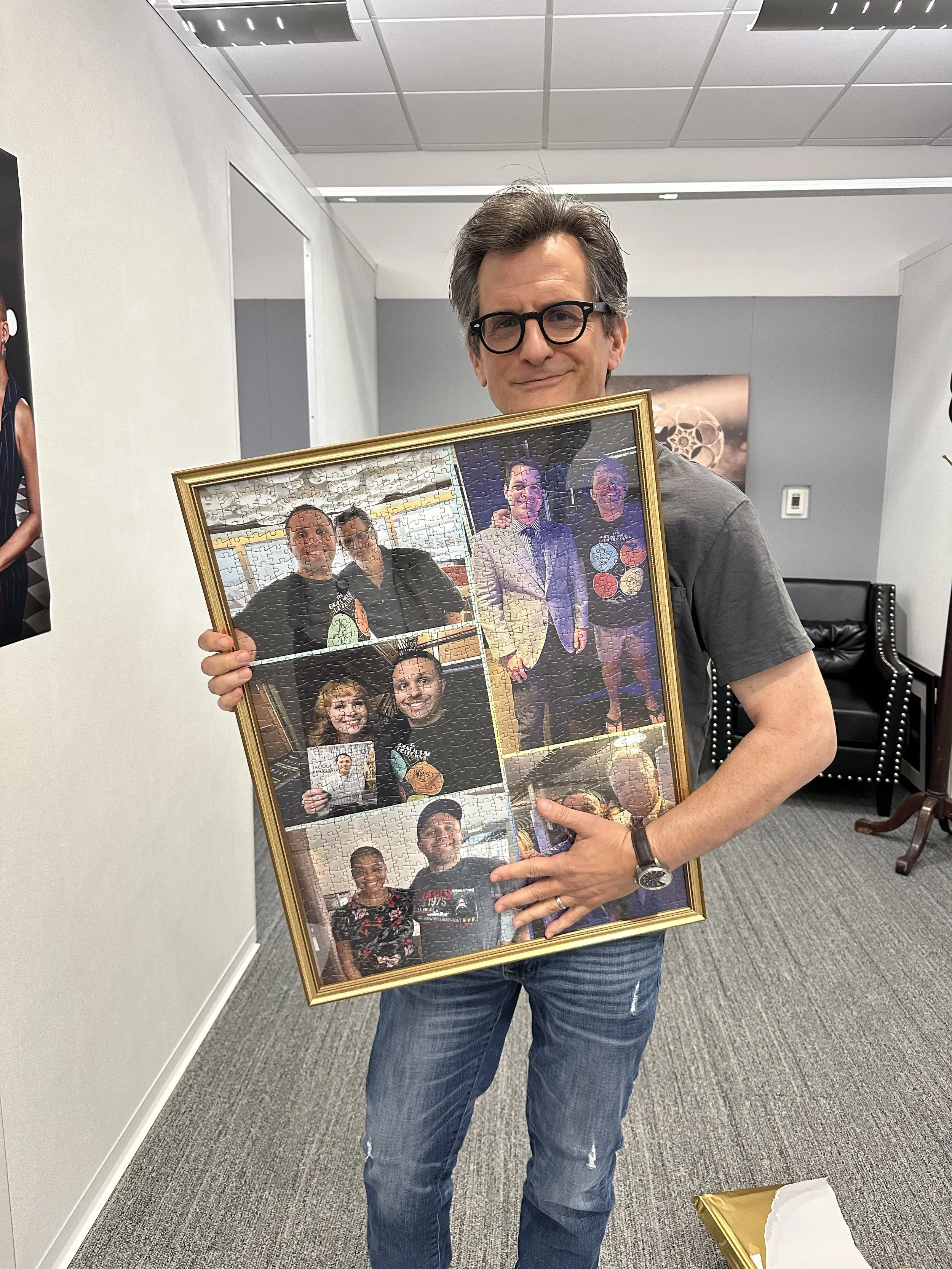 TCM host Ben Mankiewicz receiving his 1,000 piece puzzle created and bought by Jack Brait, aka Jack Of Puzzles, depicting him and the TCM hosts