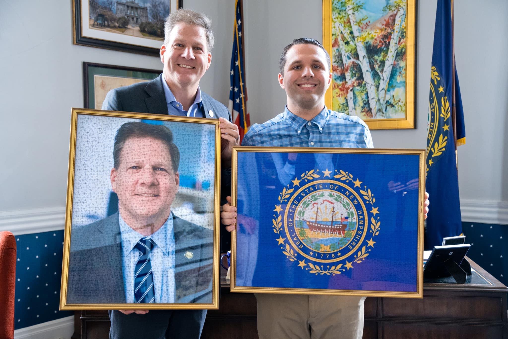 Jack Brait, aka Jack Of Puzzles, with Former New Hampshire Governor Chris Sununu at the New Hampshire State House holding two 1,000 piece puzzles that are for him of one of the state of NH seal and the other of himself, created and bought by Jack.
