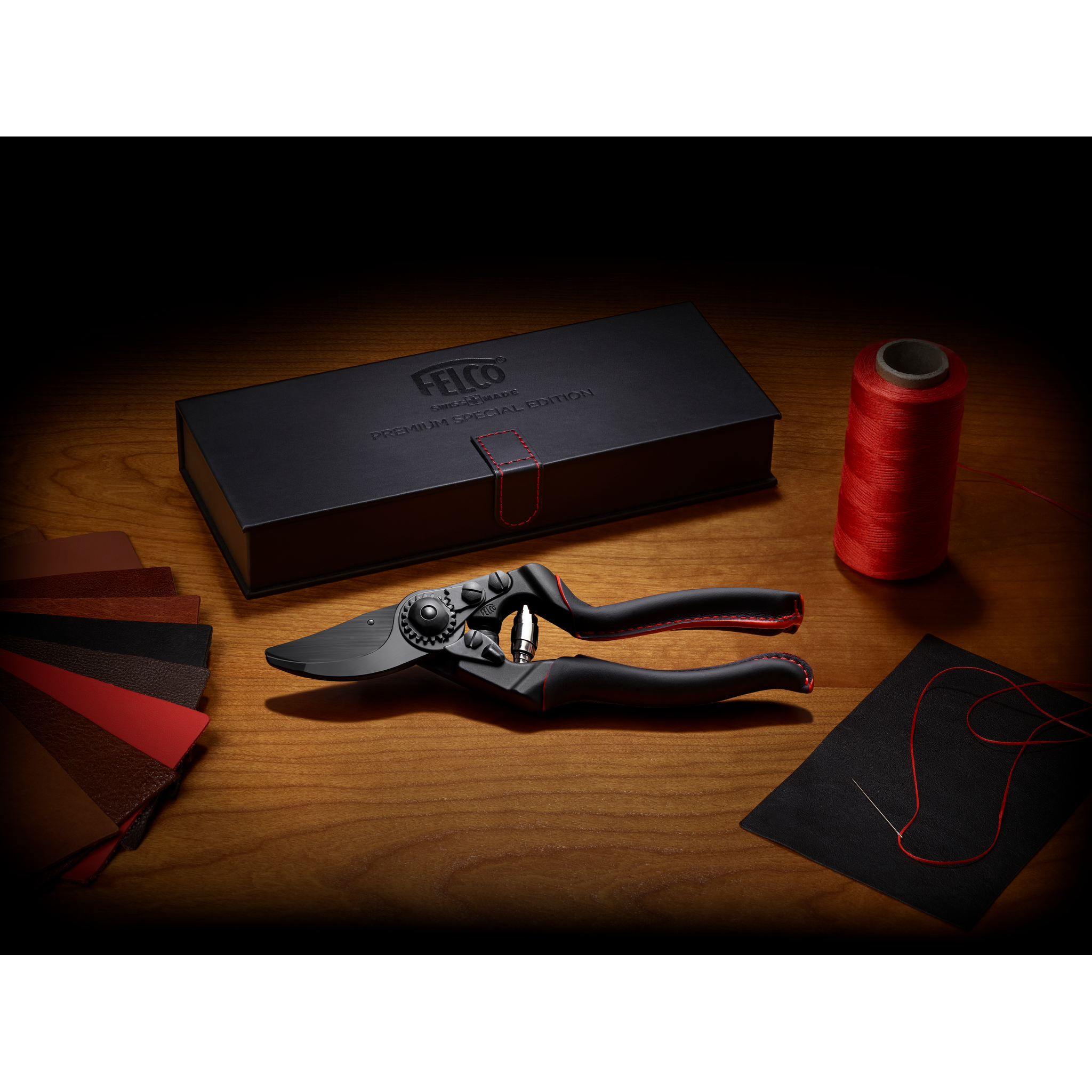 Schere, Stoffmuster, Nähgarn, Nähnadel, schwarzes Etui, rote Nähgarne, Holzoberfläche, eine spezielle Gartenschere, schwarzes Etui mit roter Naht, und einen Stoffprobeordner mit roten Stoffen