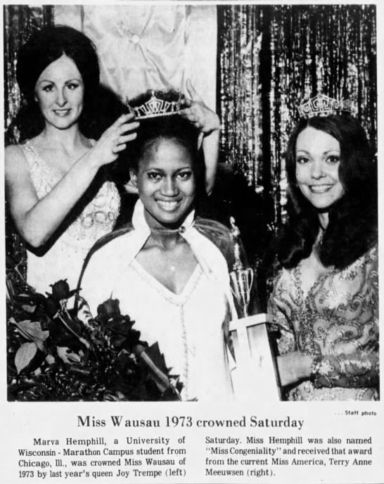 Three women, with two of them wearing crowns, celebrating Miss Wausau 1973; one woman is placing a crown on another's head, while the third woman holds a trophy. All are smiling, with bouquets of flowers in front. The background has curtains. The photo caption states Miss Wausau 1973 was crowned on Saturday, and mentions other titles and awards.