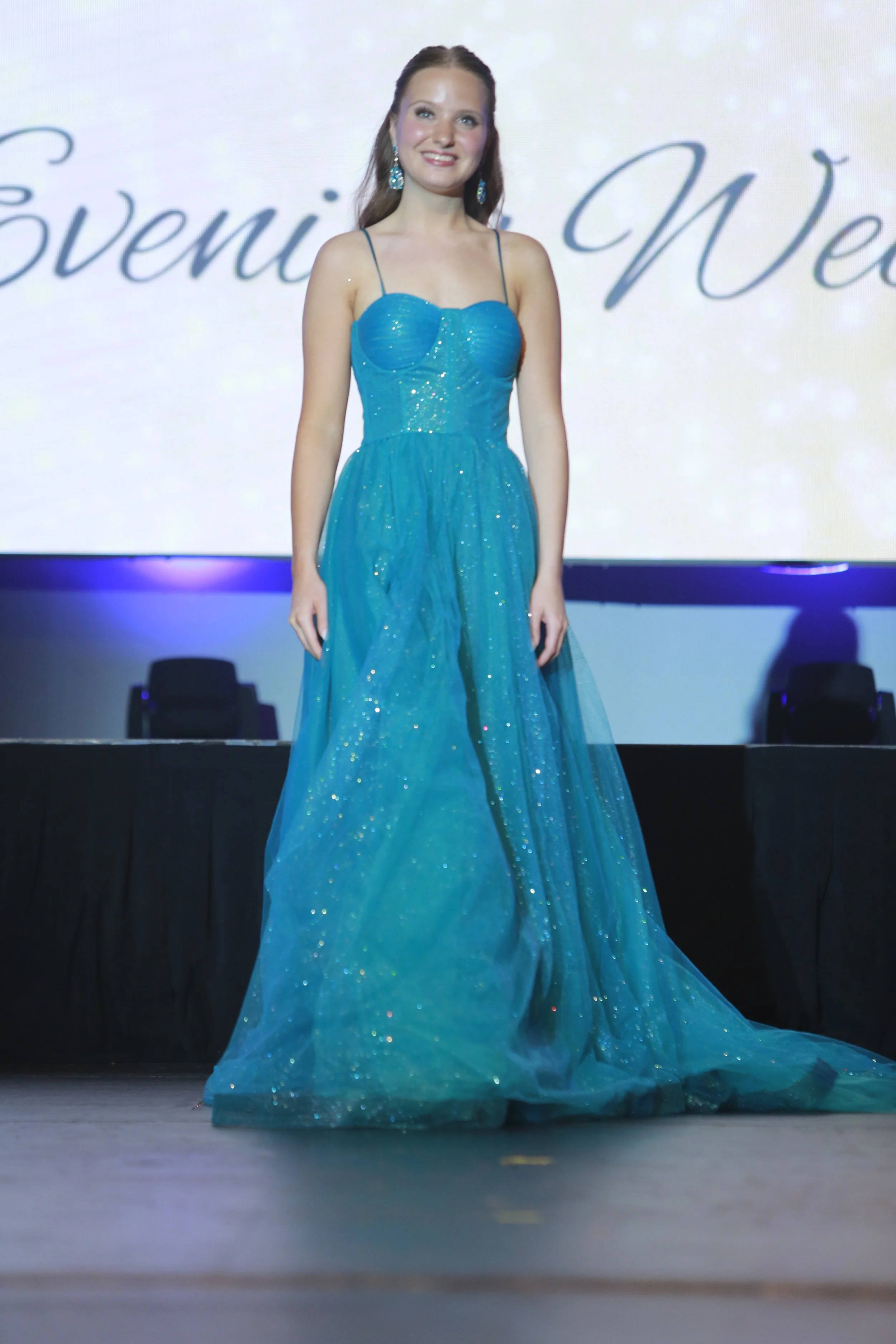A young woman in a sparkling blue evening gown stands on stage at an event. Miss Wausau Area's Teen 2025, Anna Jacobson competes at the Miss Wisconsin's Teen 2025 Competition.