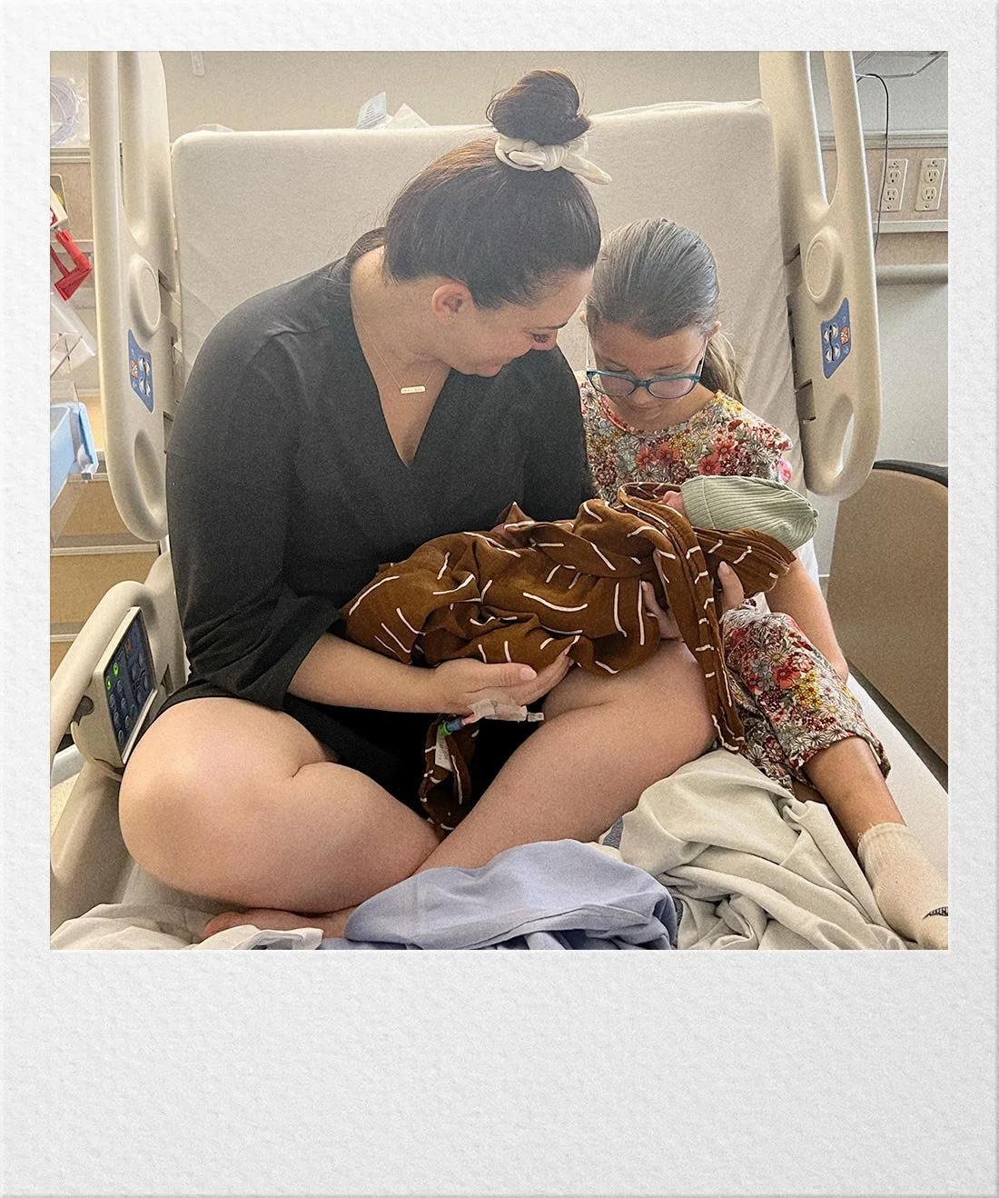 Ariel holding a newborn baby in a hospital setting.