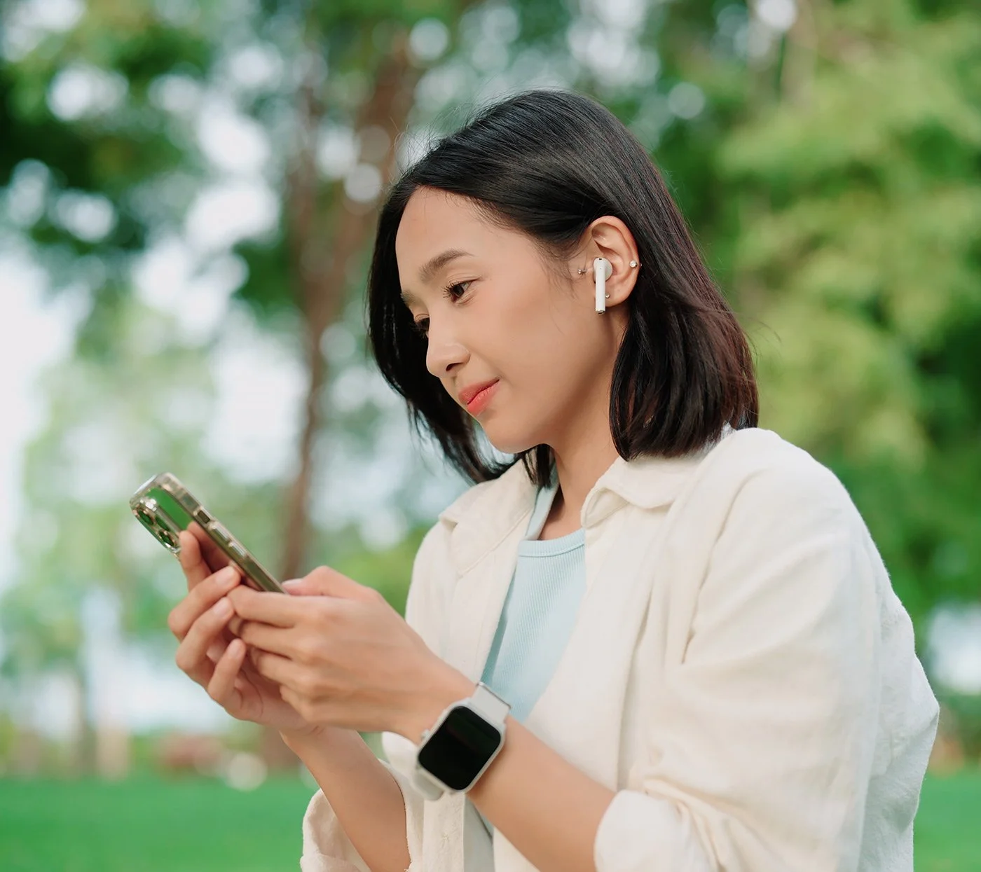 A person using a mobile phone and earbuds during an online therapy session.