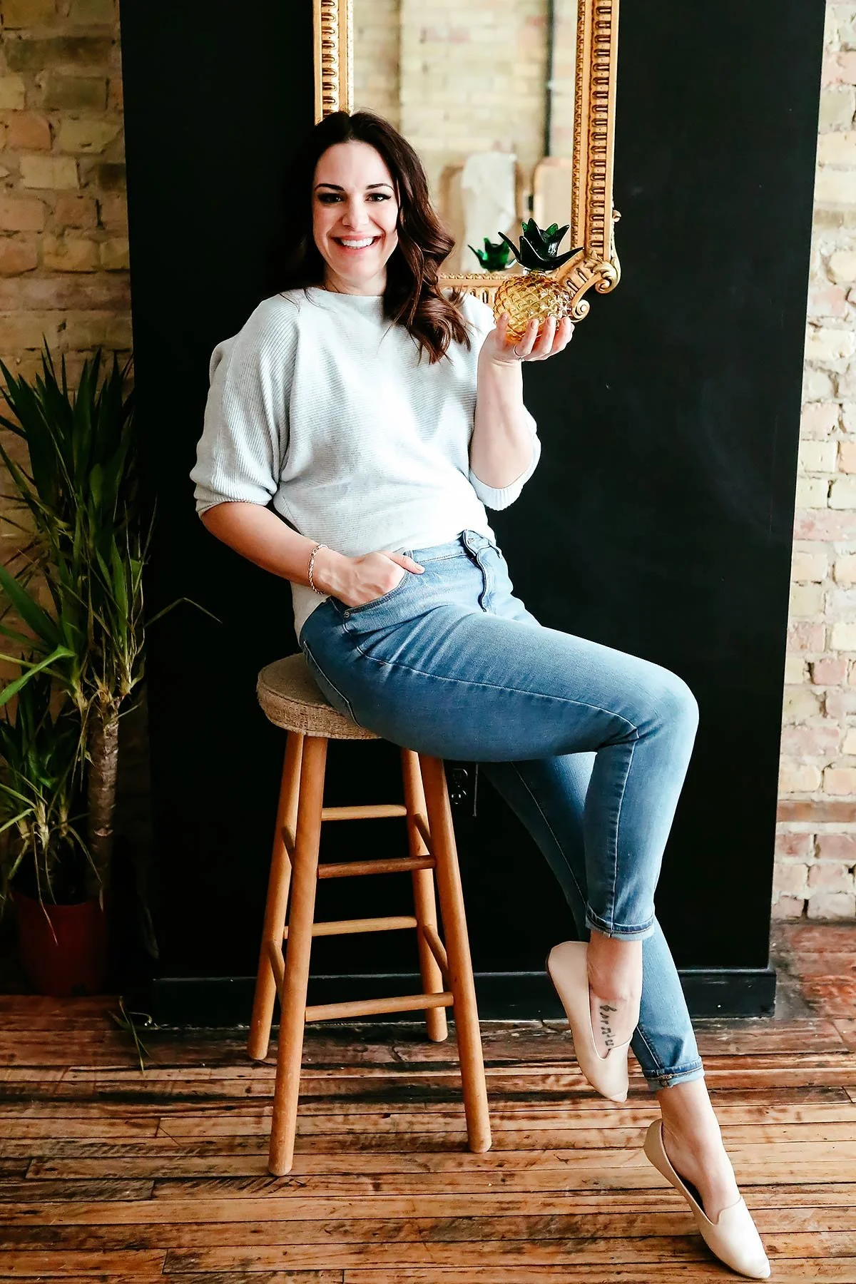 Ariel seated on a stool in a studio setting during the launch of her virtual therapy practice.