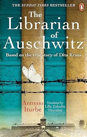 Book cover of 'The Librarian of Auschwitz' by Antonio Iturbe, based on the true story of Dita Kraus, with a background of colorful books, barbed wire, and a small guard tower.