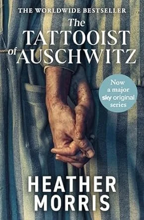 Book cover of 'The Tattooist of Auschwitz' by Heather Morris, featuring an image of clasped hands and blue and white striped fabric resembling a prison uniform.