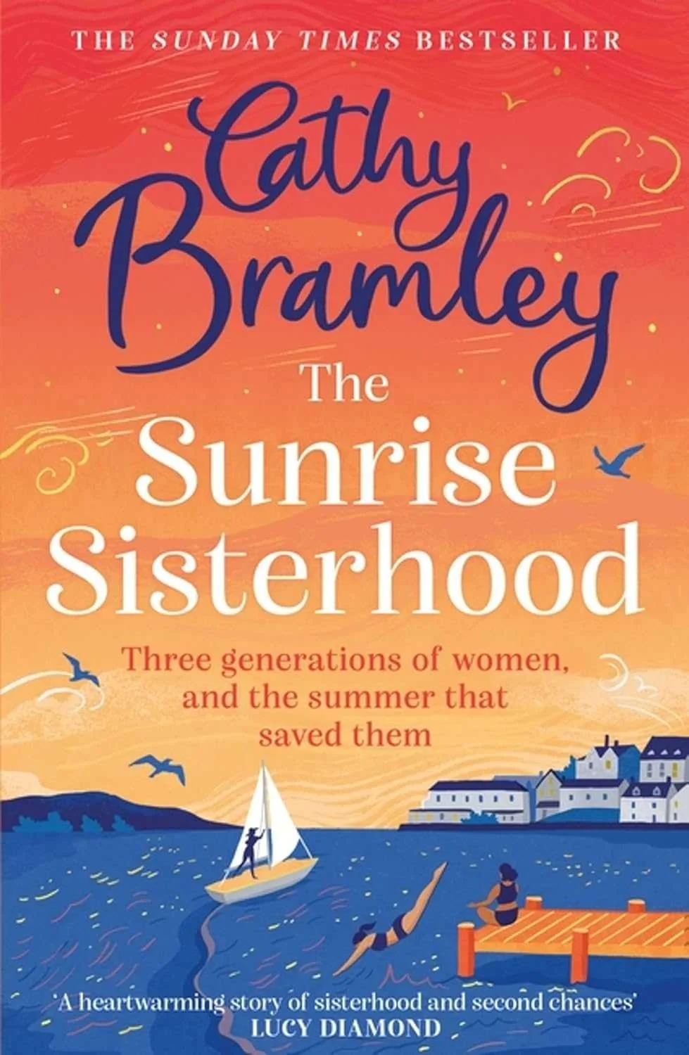 Book cover of 'The Sunrise Sisterhood' by Cathy Bramley, featuring an illustrated sunrise over a body of water with a small sailboat, a person jumping into the water, and another sitting on a dock, with houses in the background.