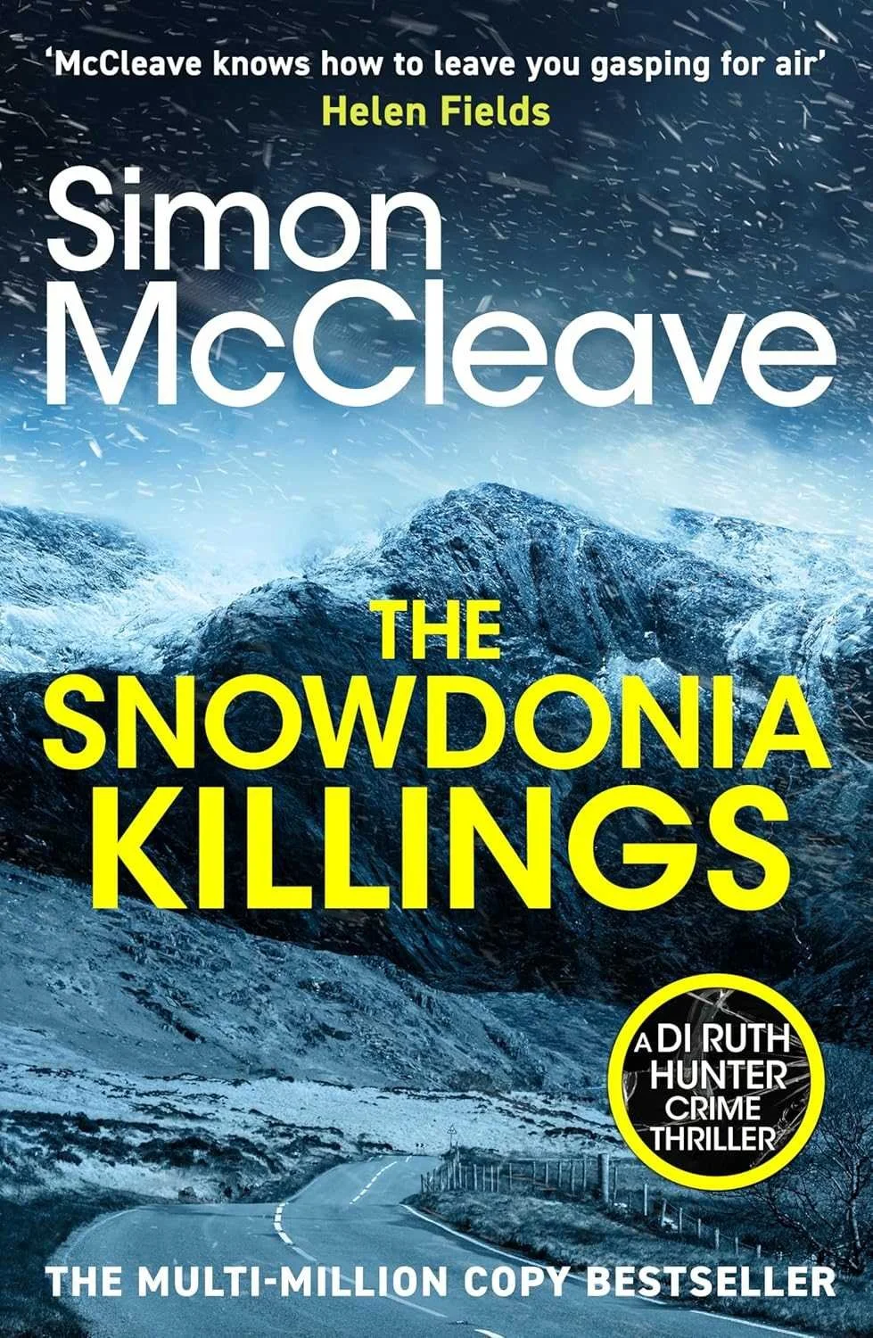 Book cover for 'The Snowdonia Killings' by Simon McCleave, featuring a snow-covered mountain landscape and a winding road, with the title in bright yellow letters and the author's name in white.