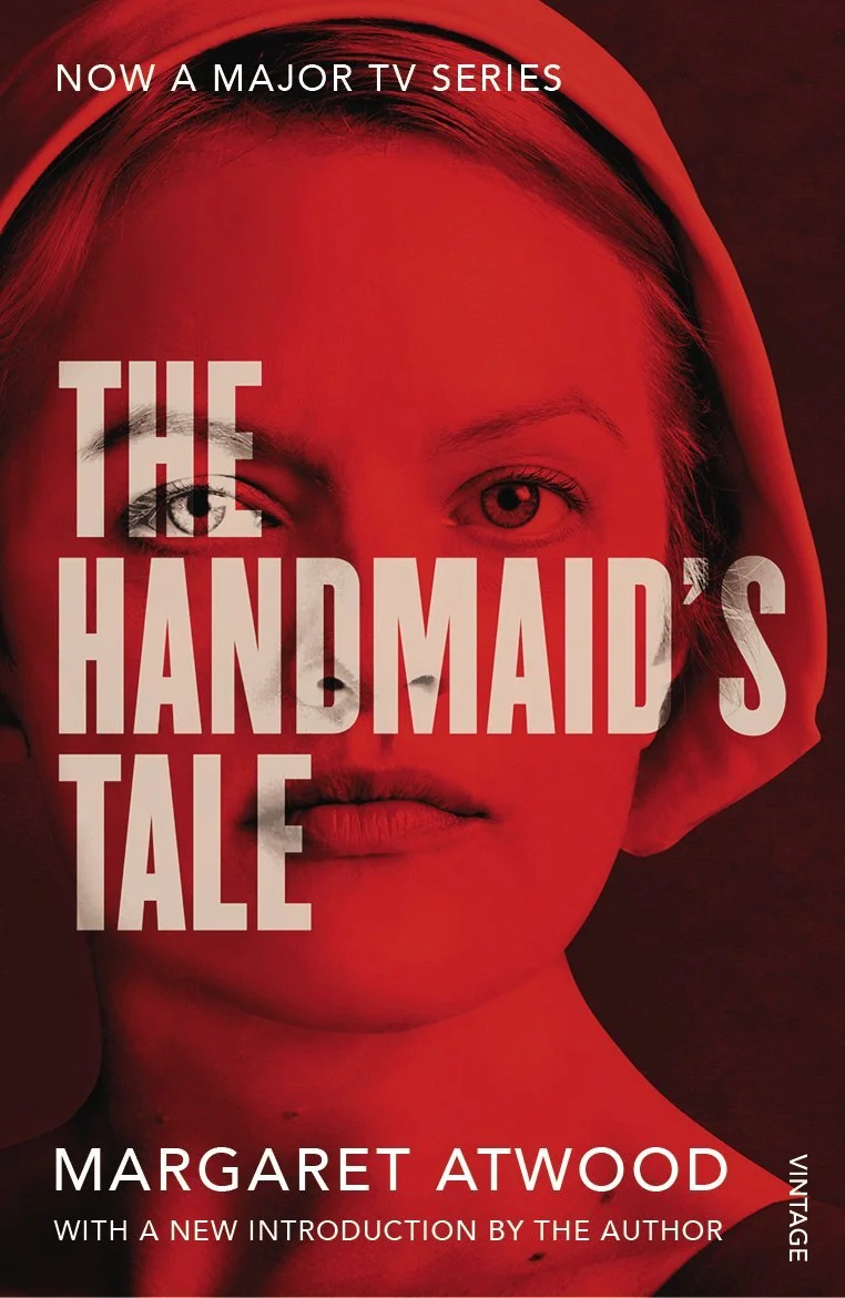 Red-tinted cover of the book "The Handmaid's Tale" by Margaret Atwood, featuring a close-up of a young woman's face, with the title and author's name on the cover.