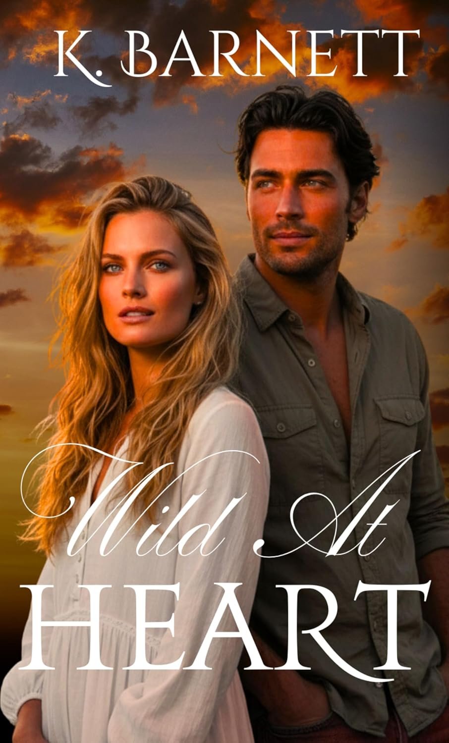 A book cover titled "Wild at Heart" by K. Barnett features a man and a woman standing outdoors during sunset, with a sky filled with orange and purple clouds in the background. The woman has long, wavy blonde hair and is wearing a white top, looking into the distance. The man has dark, wavy hair, a beard, and is wearing a khaki shirt, also looking into the distance.