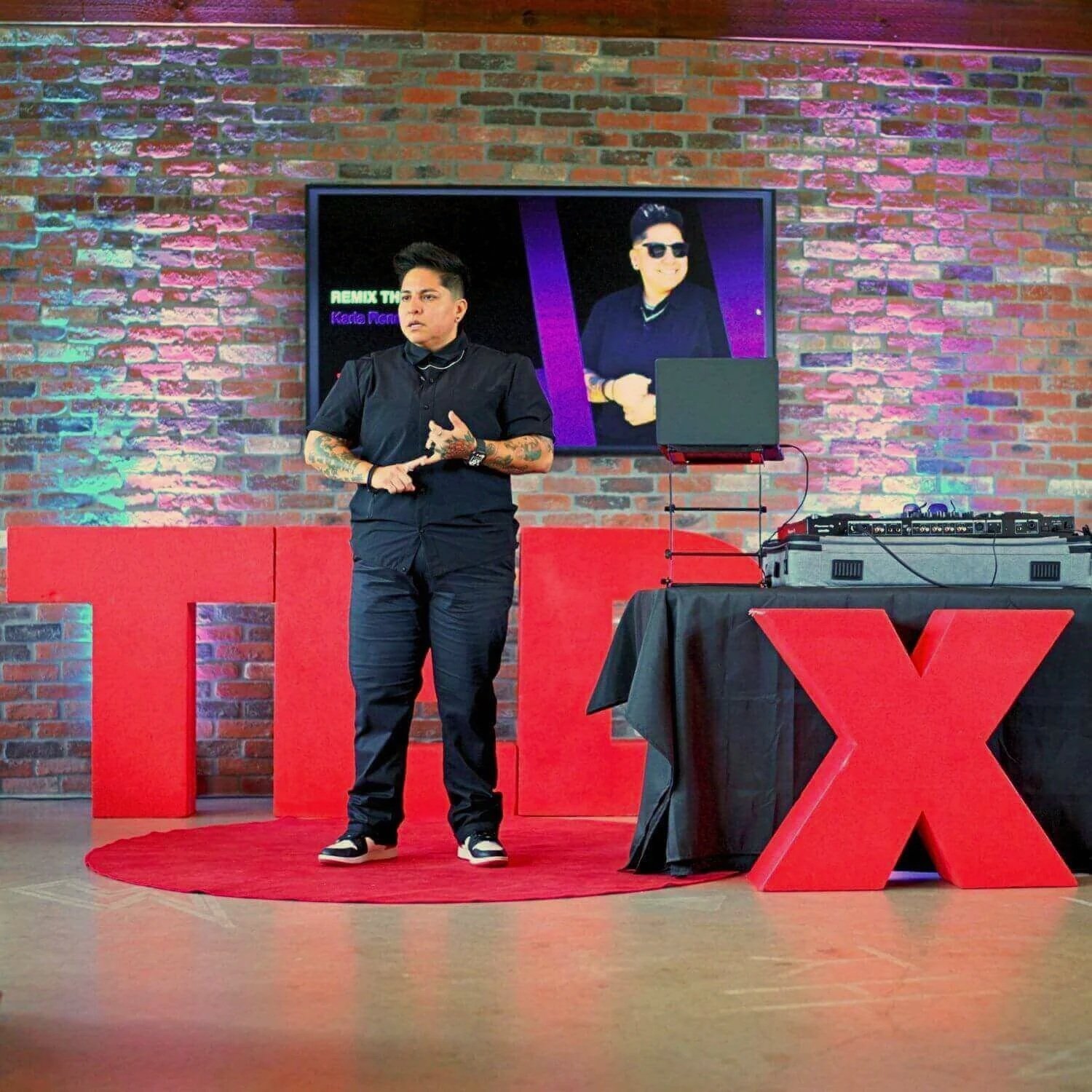 DJ KICKIT delivering a keynote presentation on stage at a TEDx event
