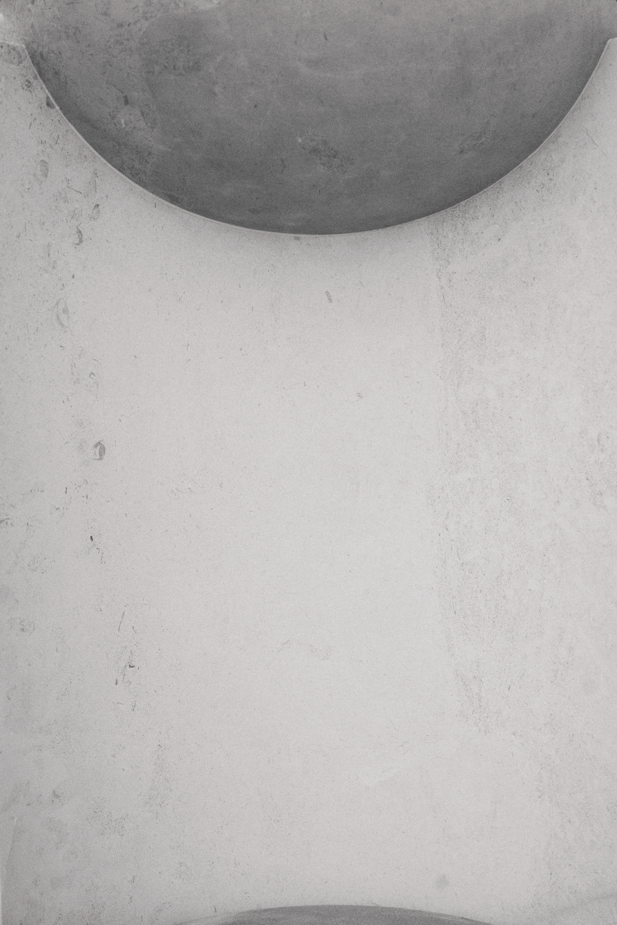 Top view of a white textured surface with a circular metallic object at the top edge.