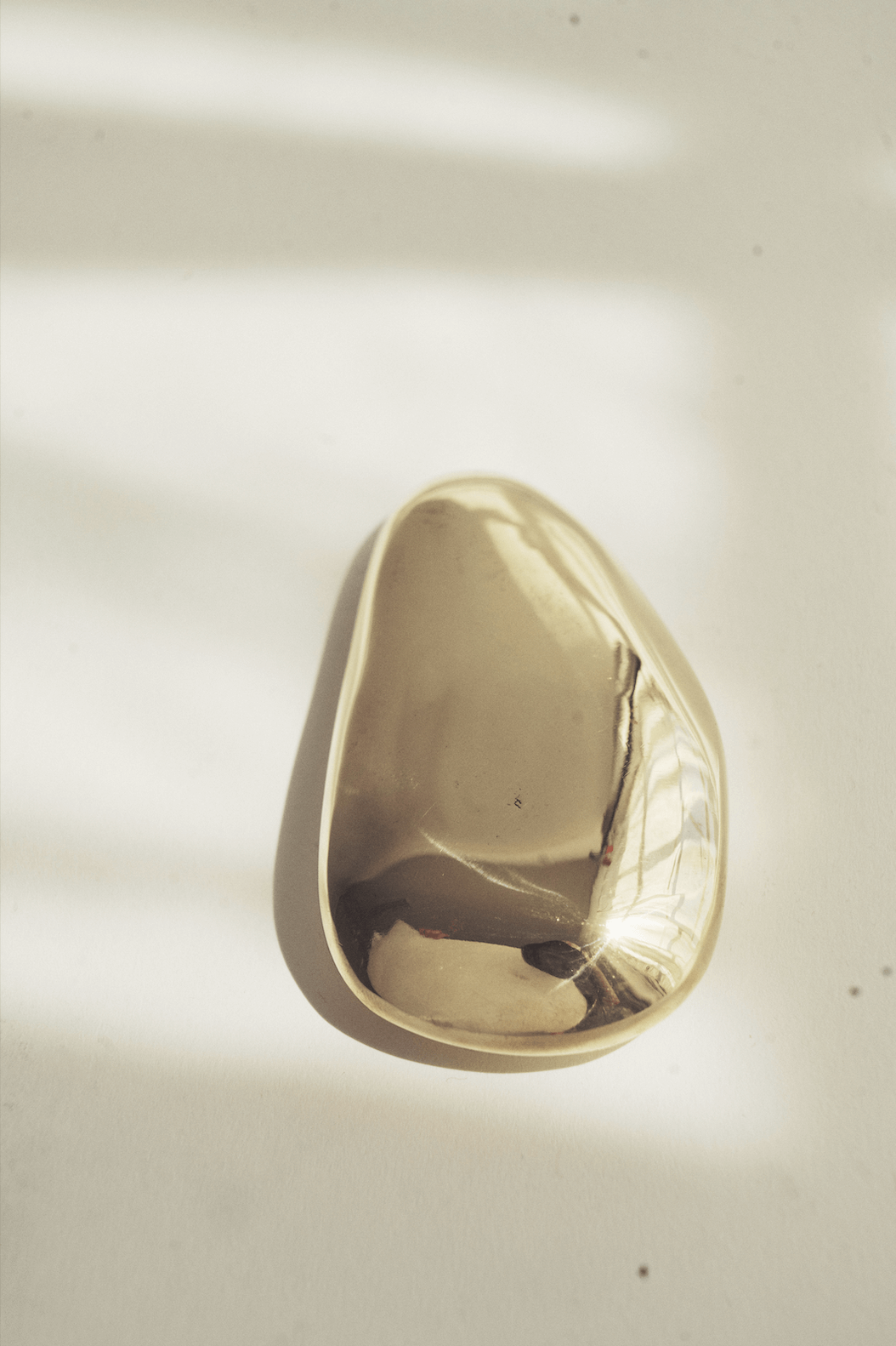 Close-up of a shiny, metallic, gold-colored cone-shaped object on a plain background.