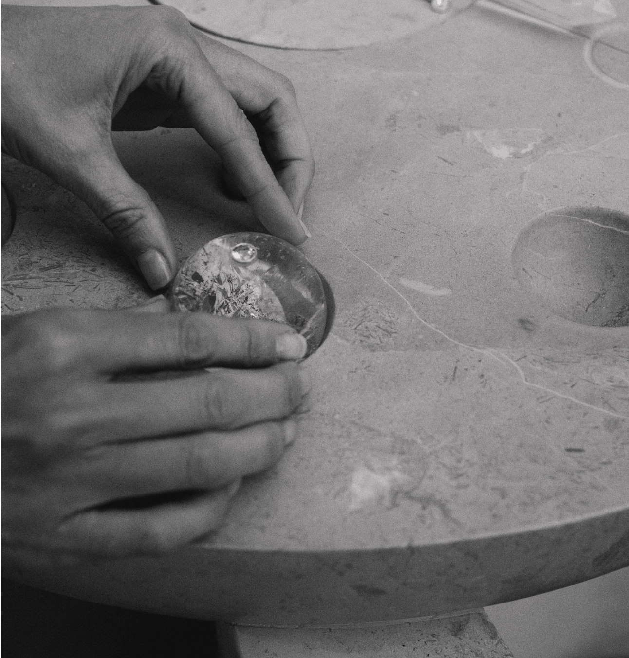 Person shaping a glass object on a workbench in a workshop.