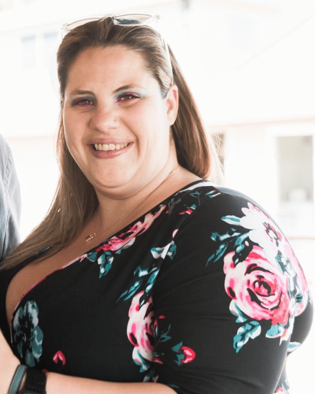 A woman is pictured smiling at the camera, wearing a black, floral dress.