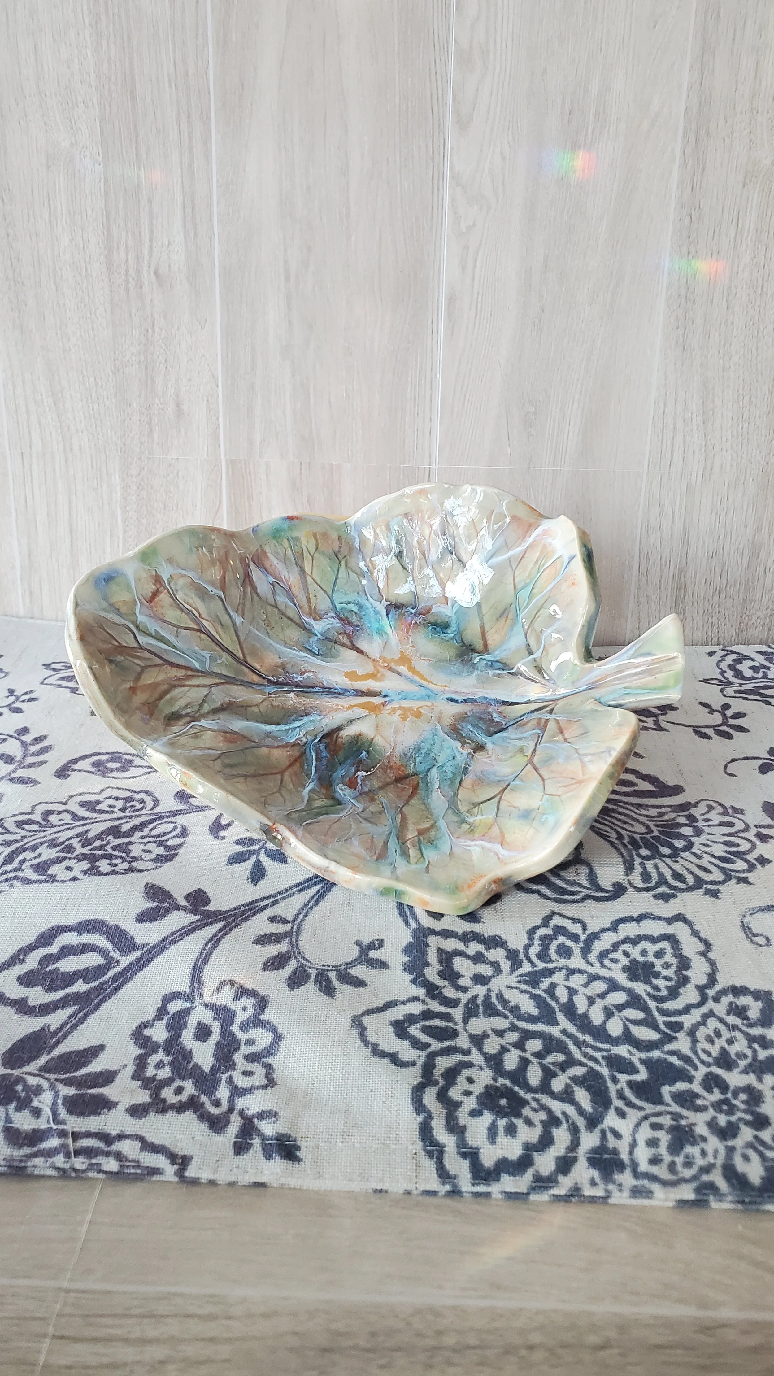 A colorful, leaf-shaped ceramic dish with a glossy finish.