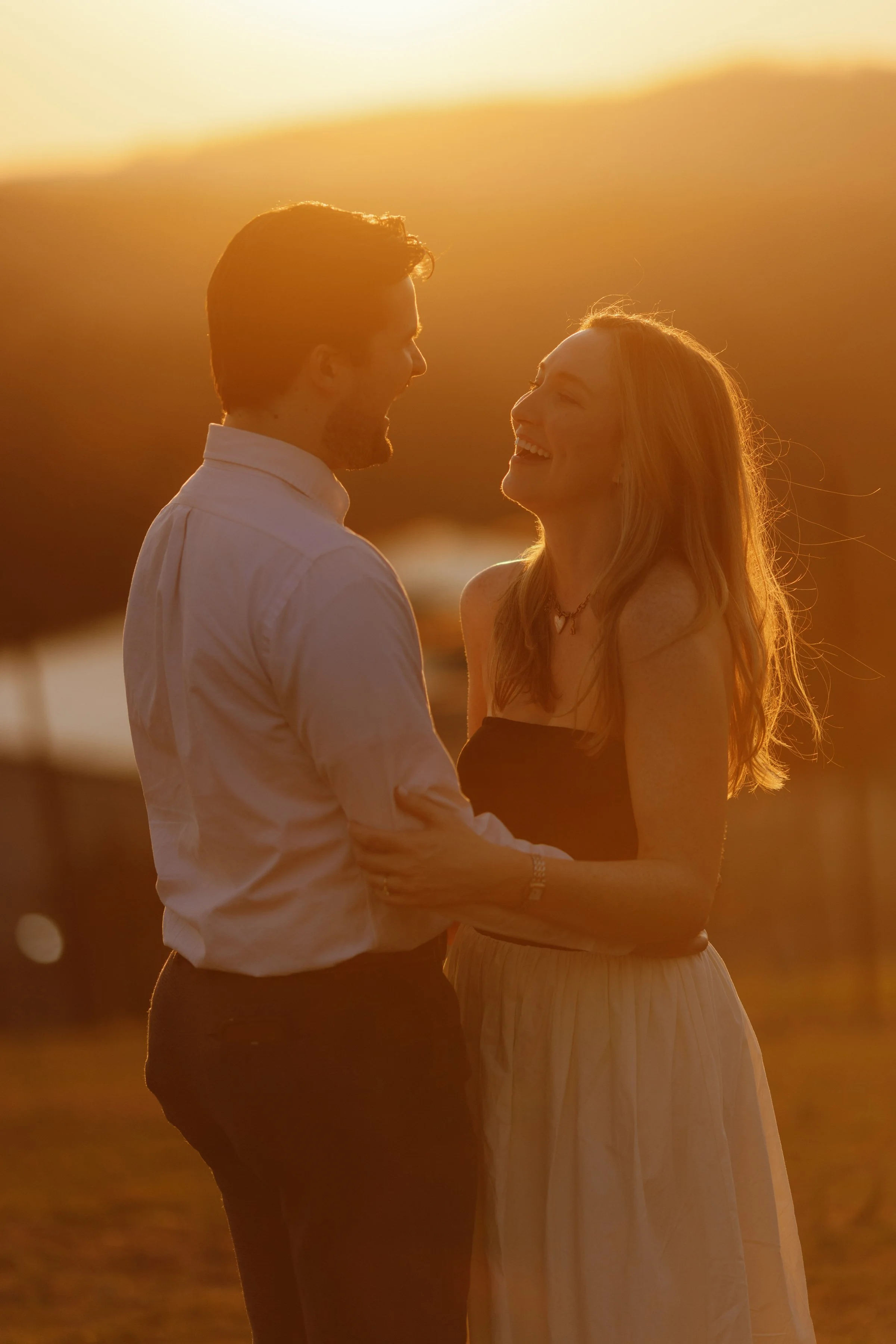 Sunset portrait of surprise proposal engaged couple smiling at each other