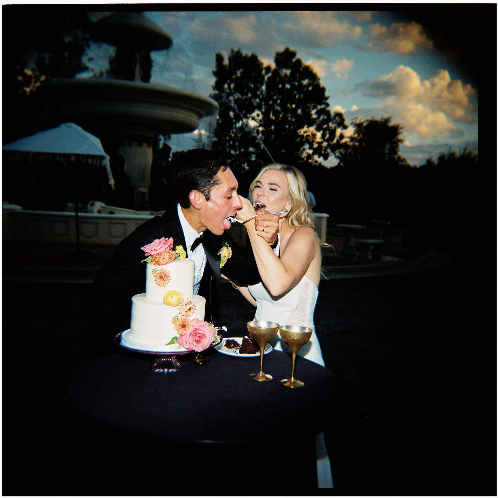 Film photo of a bride and groom eating their wedding cake