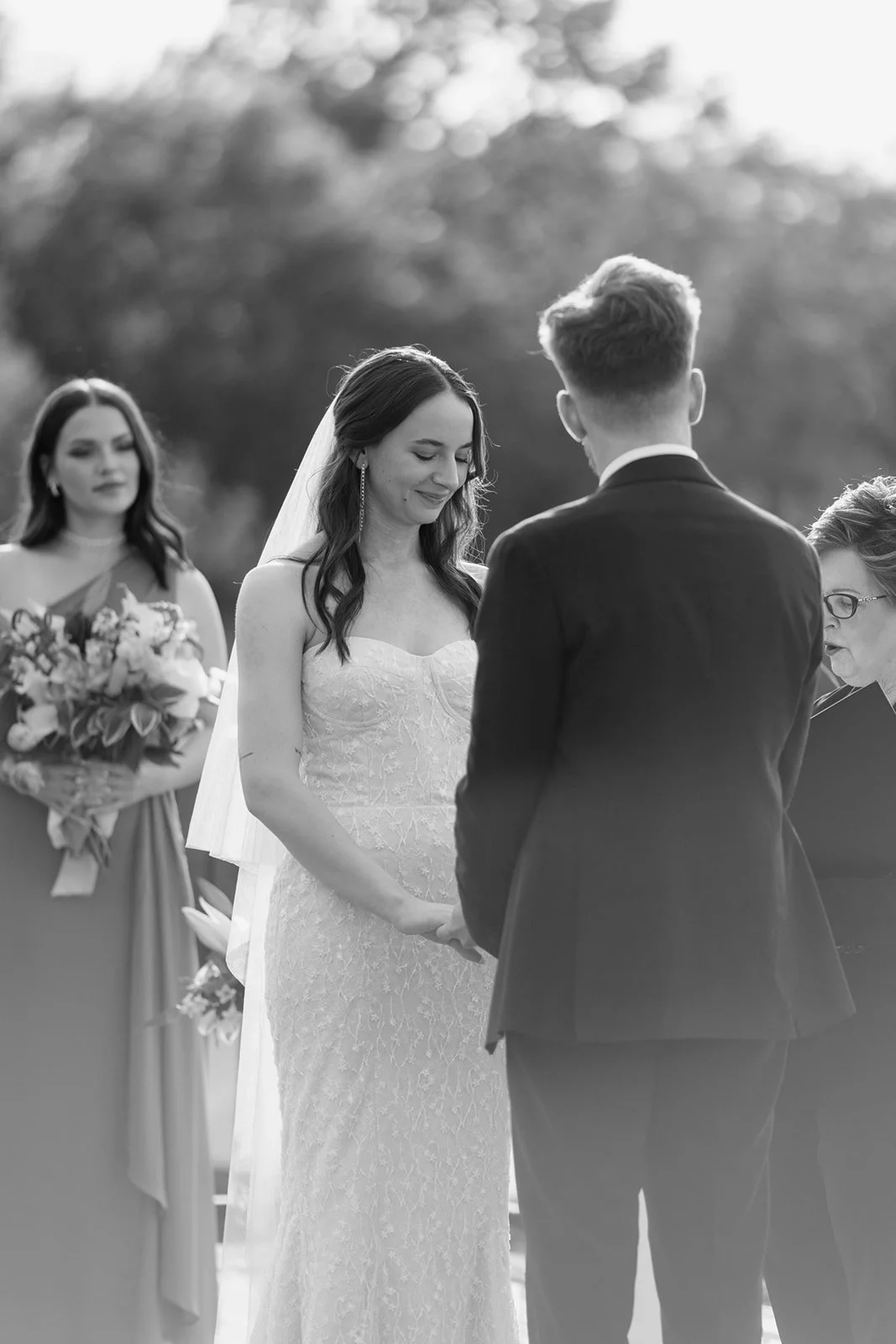 Black and white photo of bride and groom holding hands and looking down