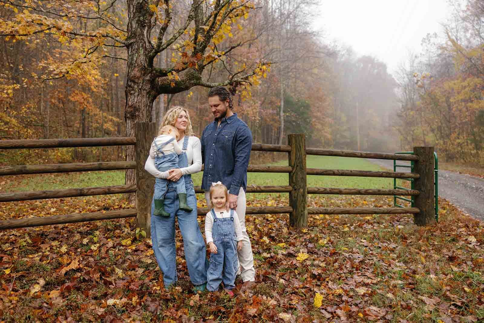 Family of four surrounded by fall foliage wearing denim and blue