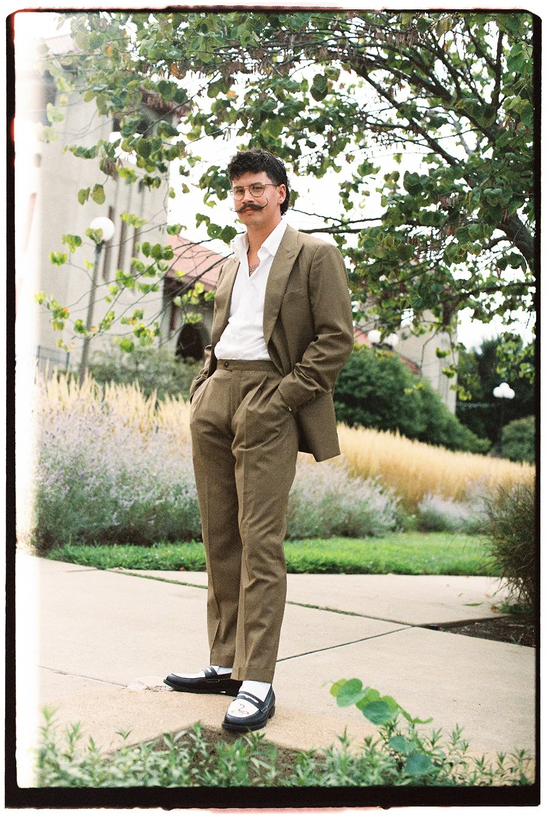 Film photo of groom portrait standing outside posing in his tan suit