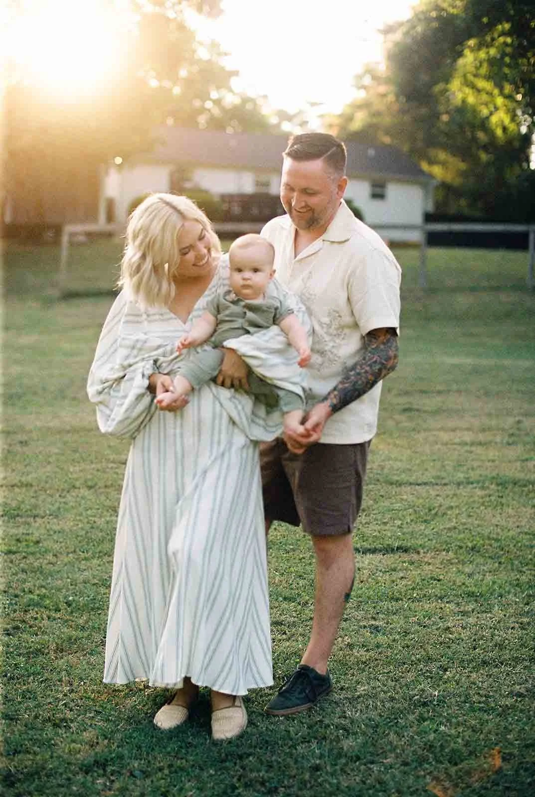 Film photo of mom holding a baby with dad looking at them both