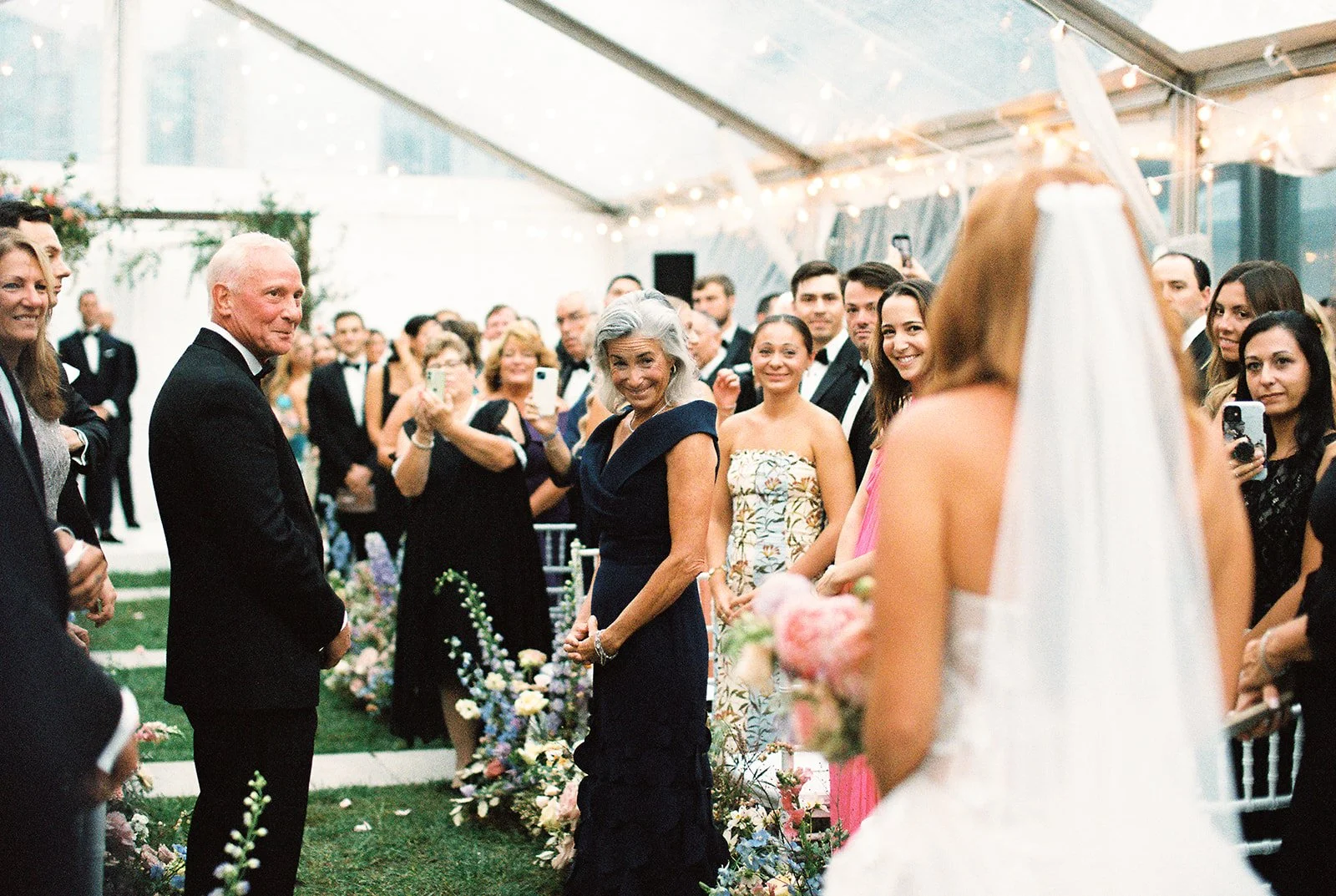 Bride walking down the aisle of her wedding ceremony with guests standing and smiling