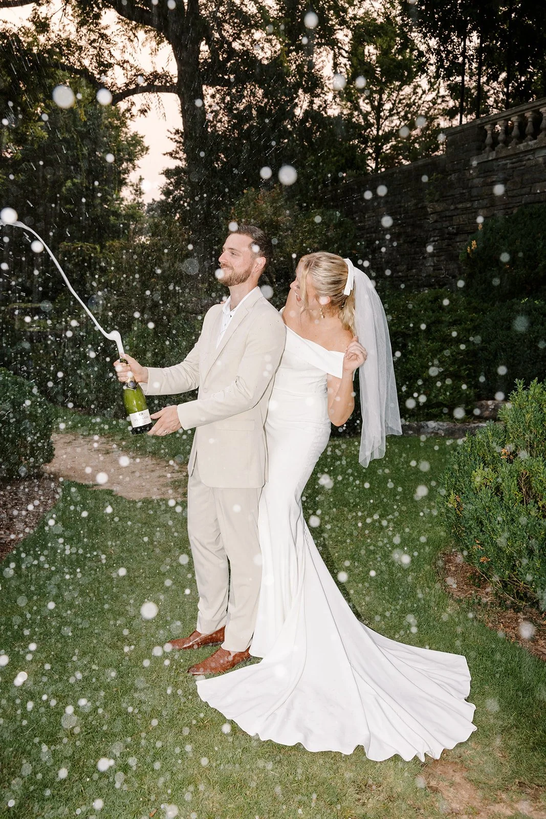 Bride and groom popping champagne at Cheekwood Gardens during golden hour