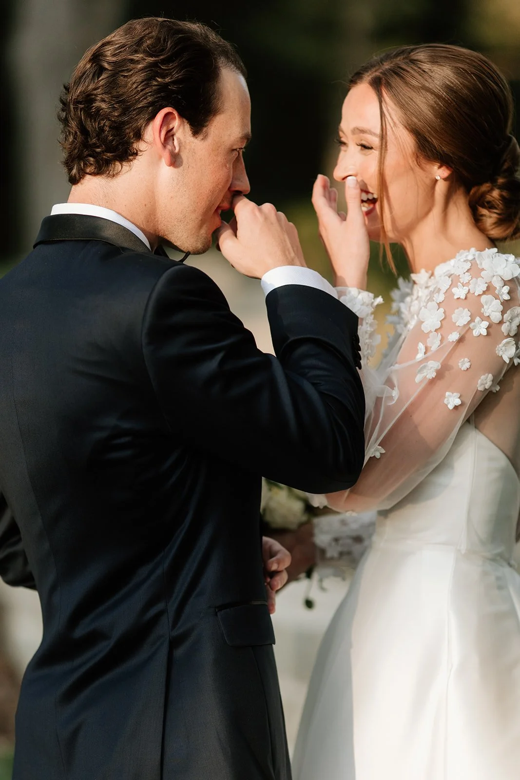 A bride and groom share a moment of laughter during their wedding outdoors.