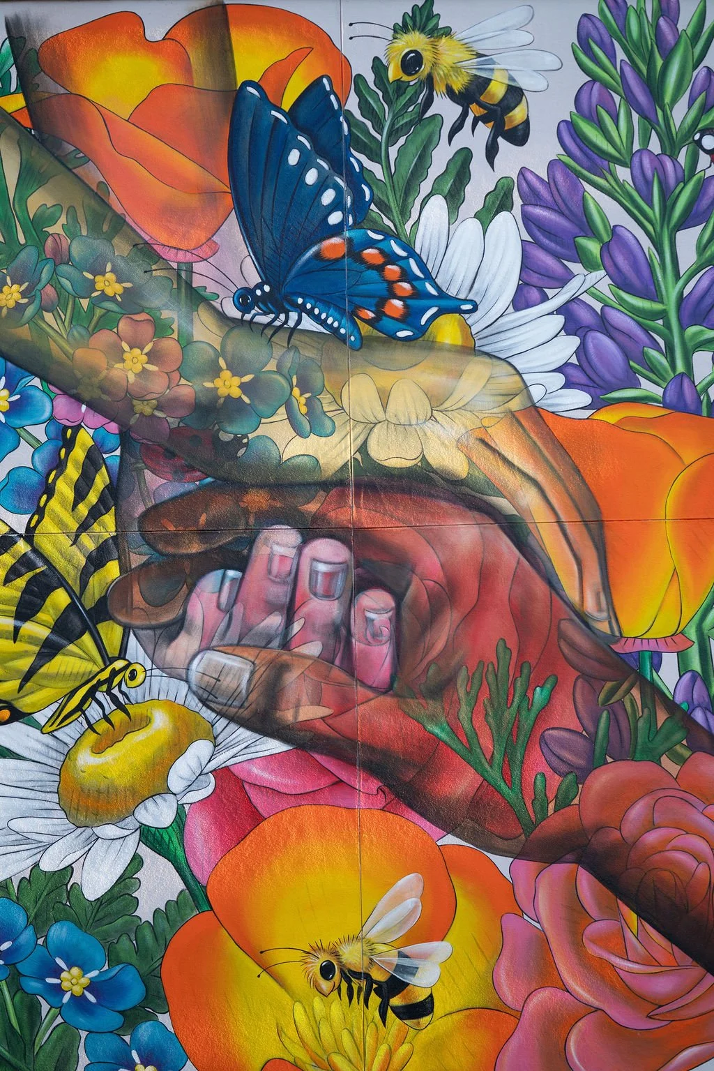 Colorful mural with bees, butterfly, flowers, and a human hand.