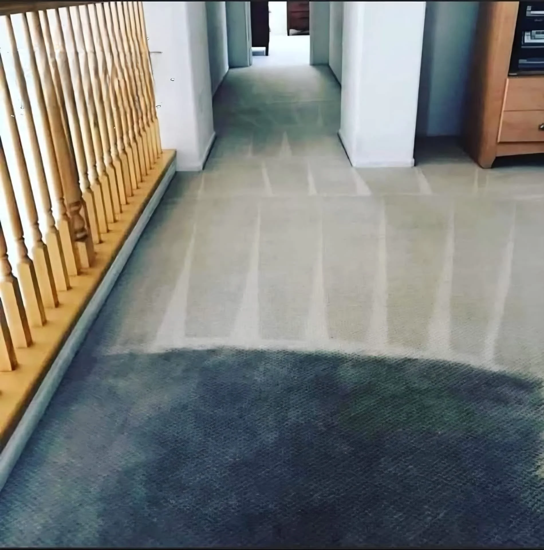 Indoor hallway with wooden slat wall on left, light-colored tiled floor, white walls, and at the end, a painting on the wall with doorway and furniture visible.