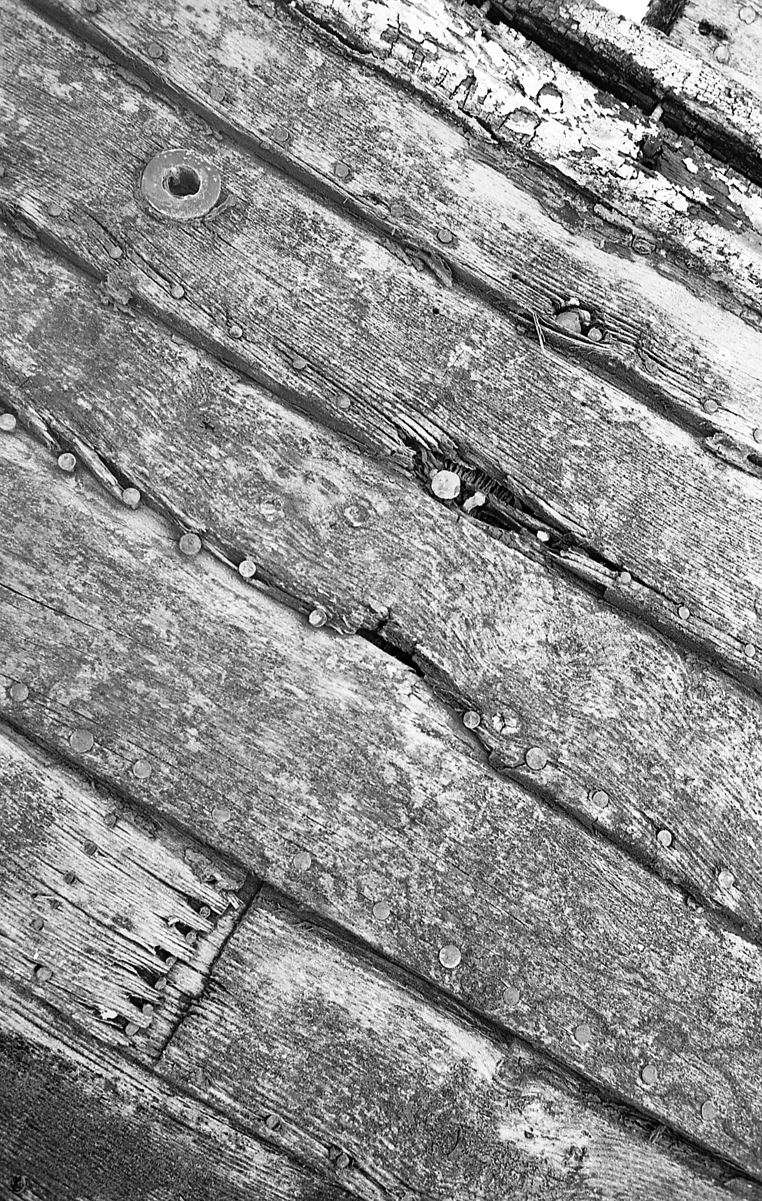Close-up of weathered wooden planks with rusted nails and peeling paint.