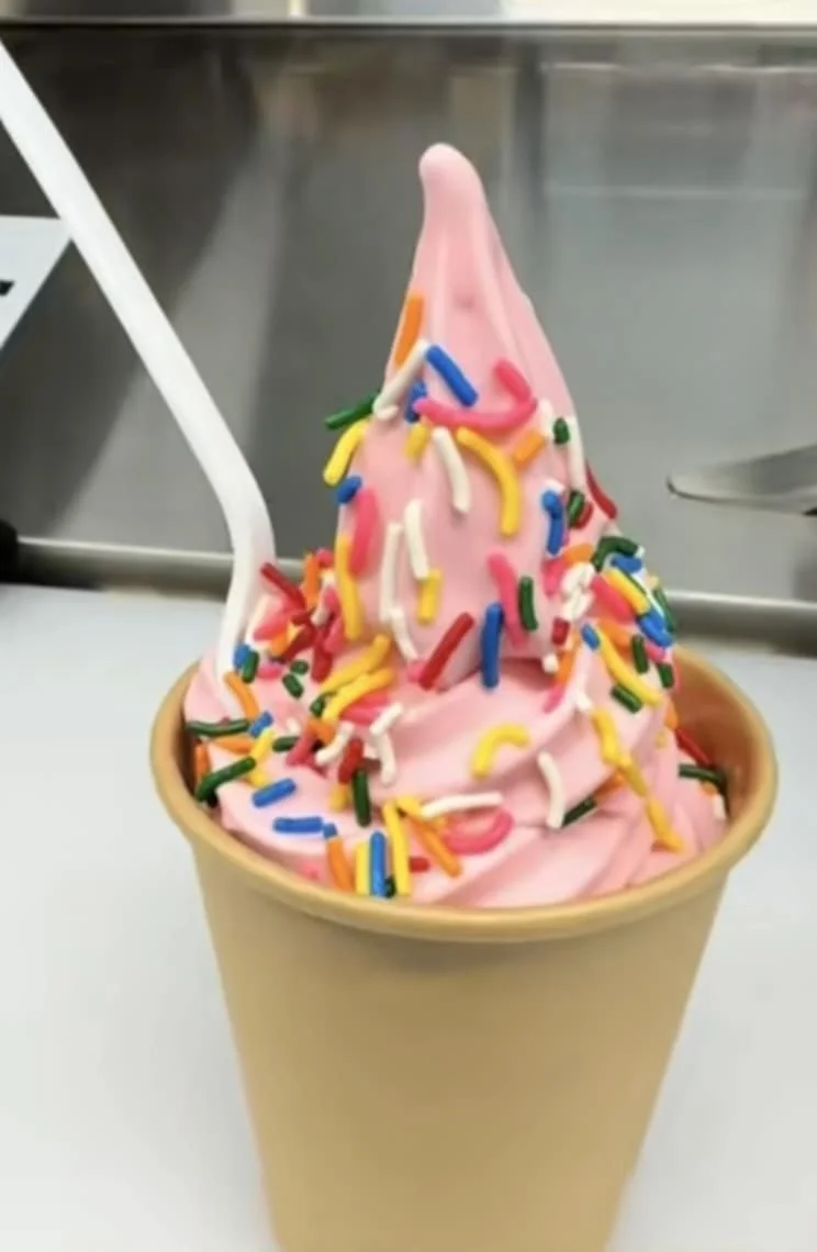 Une crème glacée à la vanille avec des vermicelles colorés dans un cône en papier