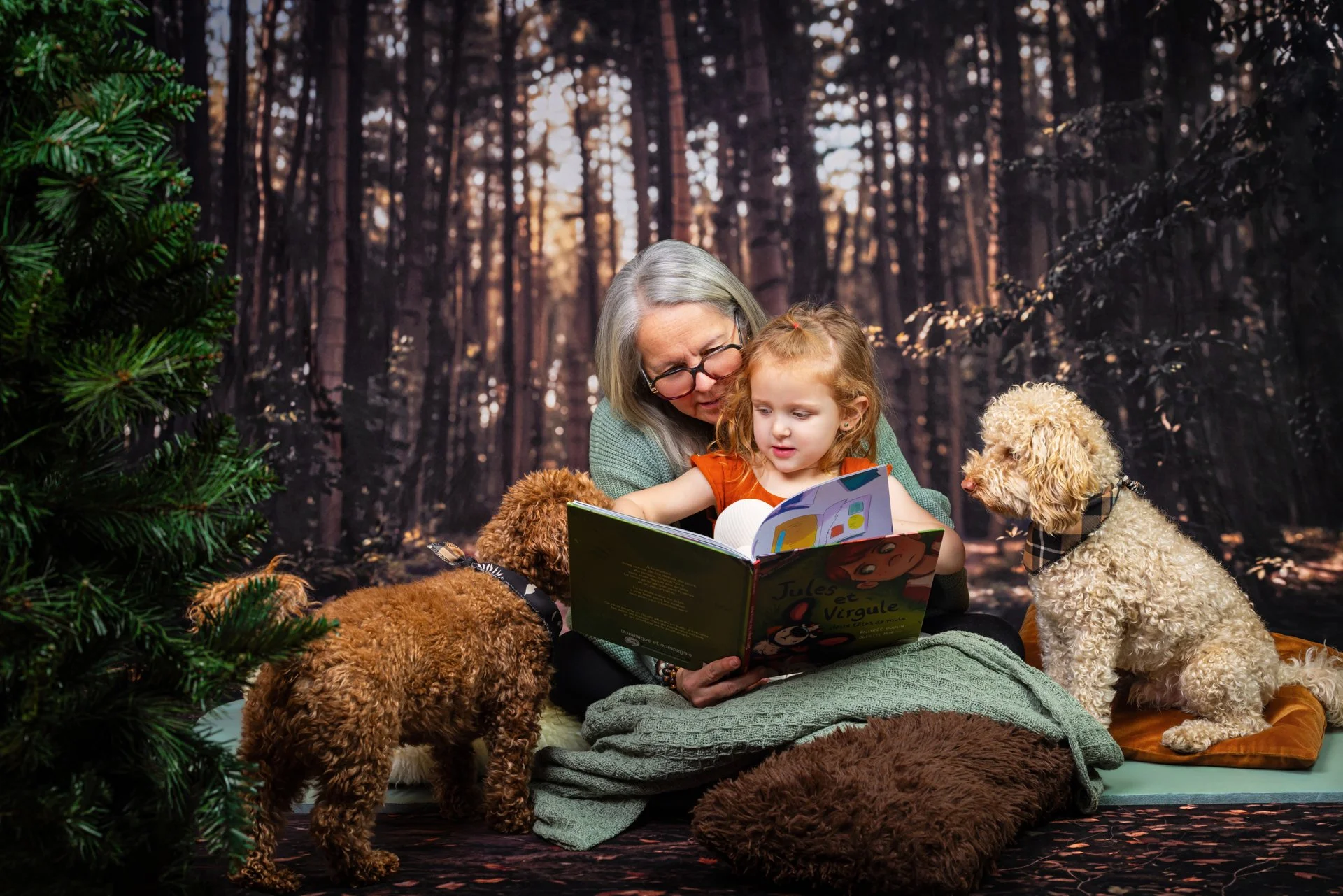 Une grand-mère lisant un livre à une jeune fille entourées de trois chiens dans une forêt.