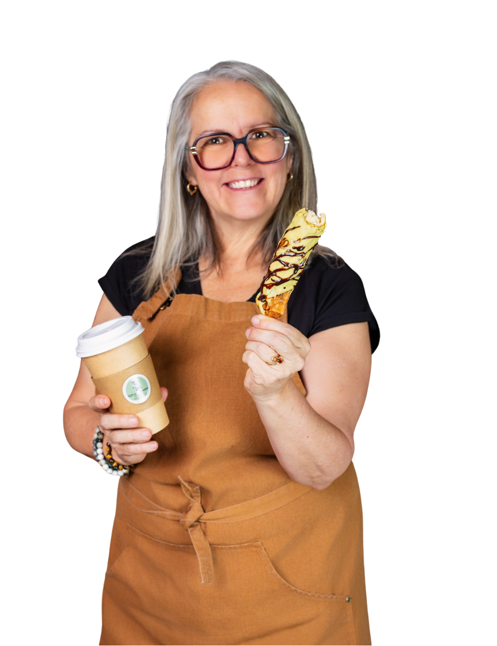 Une femme souriante portant des lunettes, une robe noire et un tablier en cuir, tenant un cône glacé avec du chocolat et de la vanille, et une tasse à café en papier.