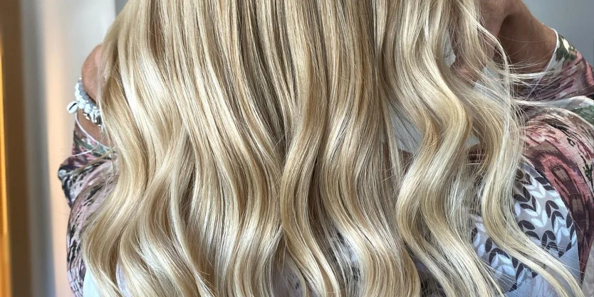 Back of a person with long, straight, shiny reddish-brown hair in a salon setting.