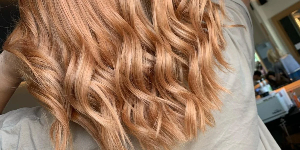 Close-up of long, wavy, strawberry blonde hair with loose curls.